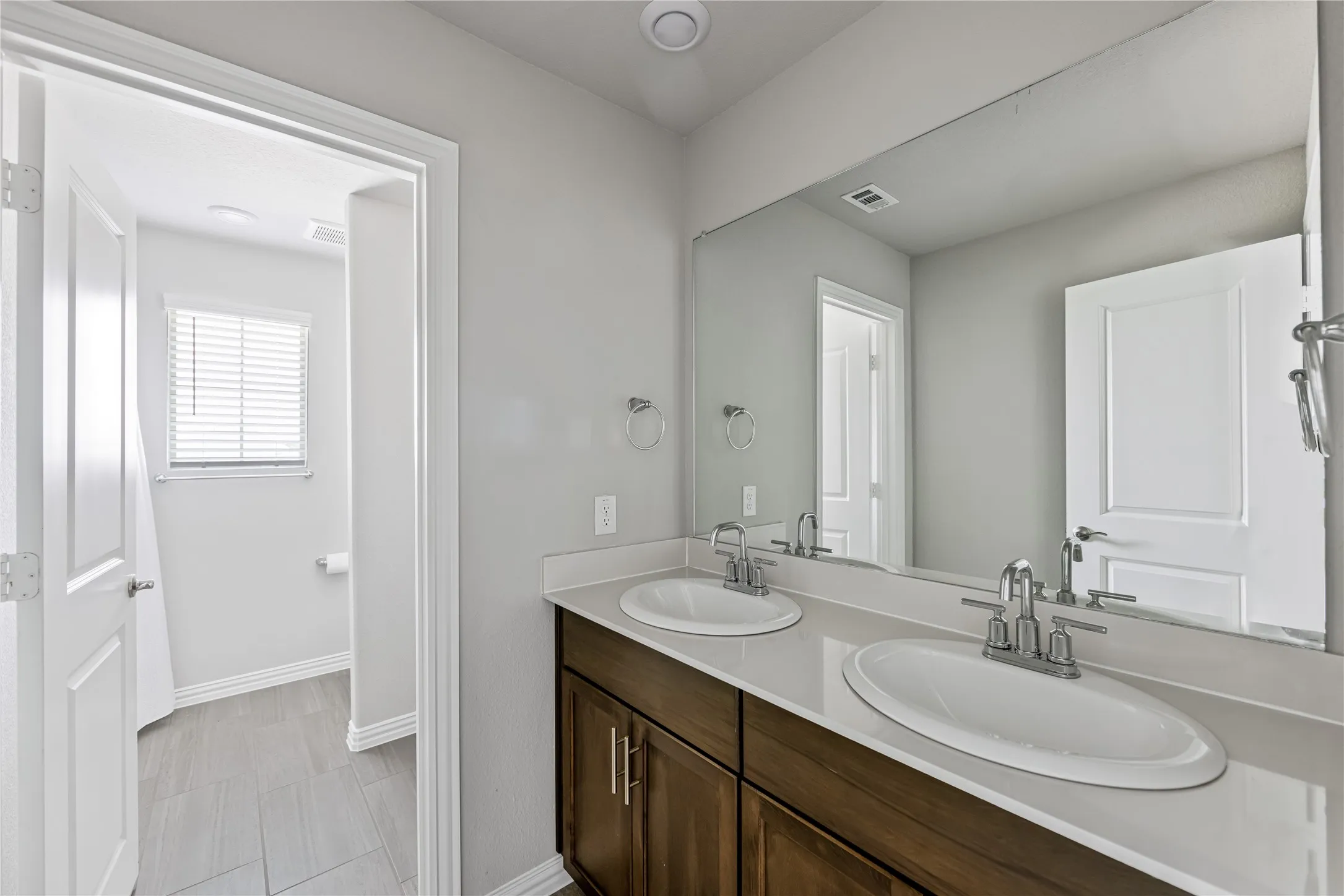 Dual vanity with undermount sinks, chrome fixtures, and a white countertop