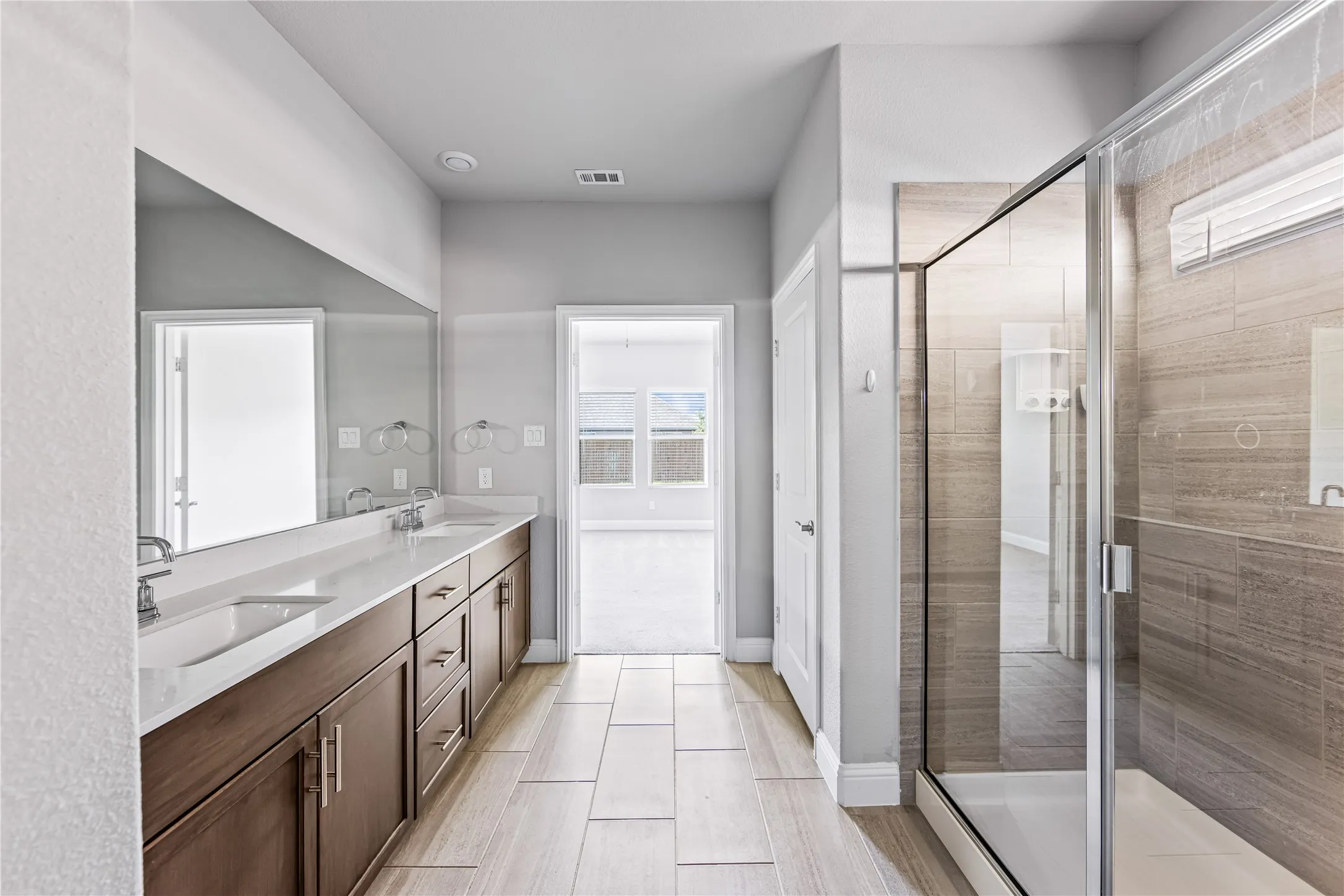 Double vanity with undermount sinks, white countertop, and expansive wall-mounted mirror