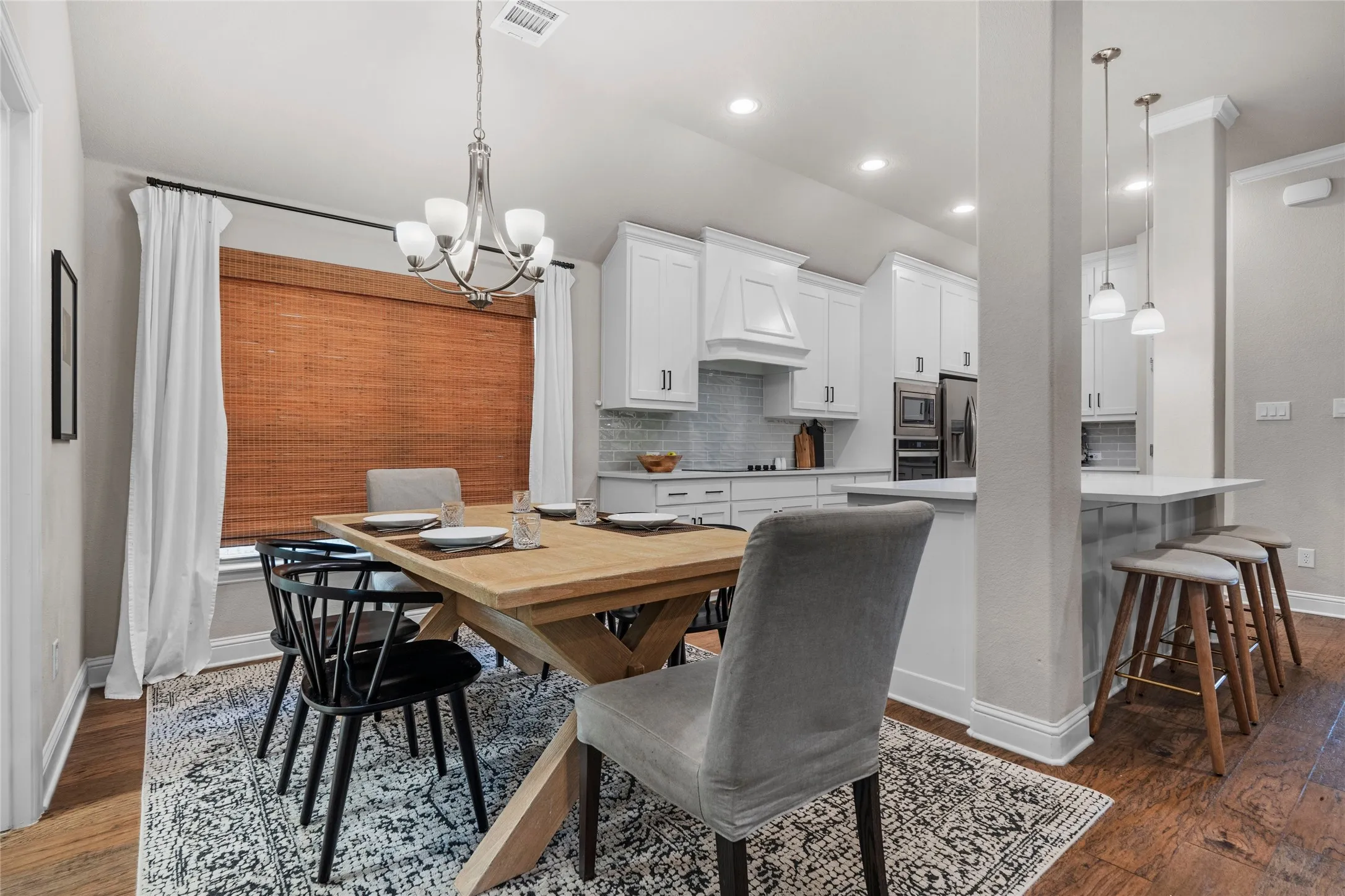 Hardwood-finish flooring, recessed lighting, and a chandelier illuminate the dining area and kitchen