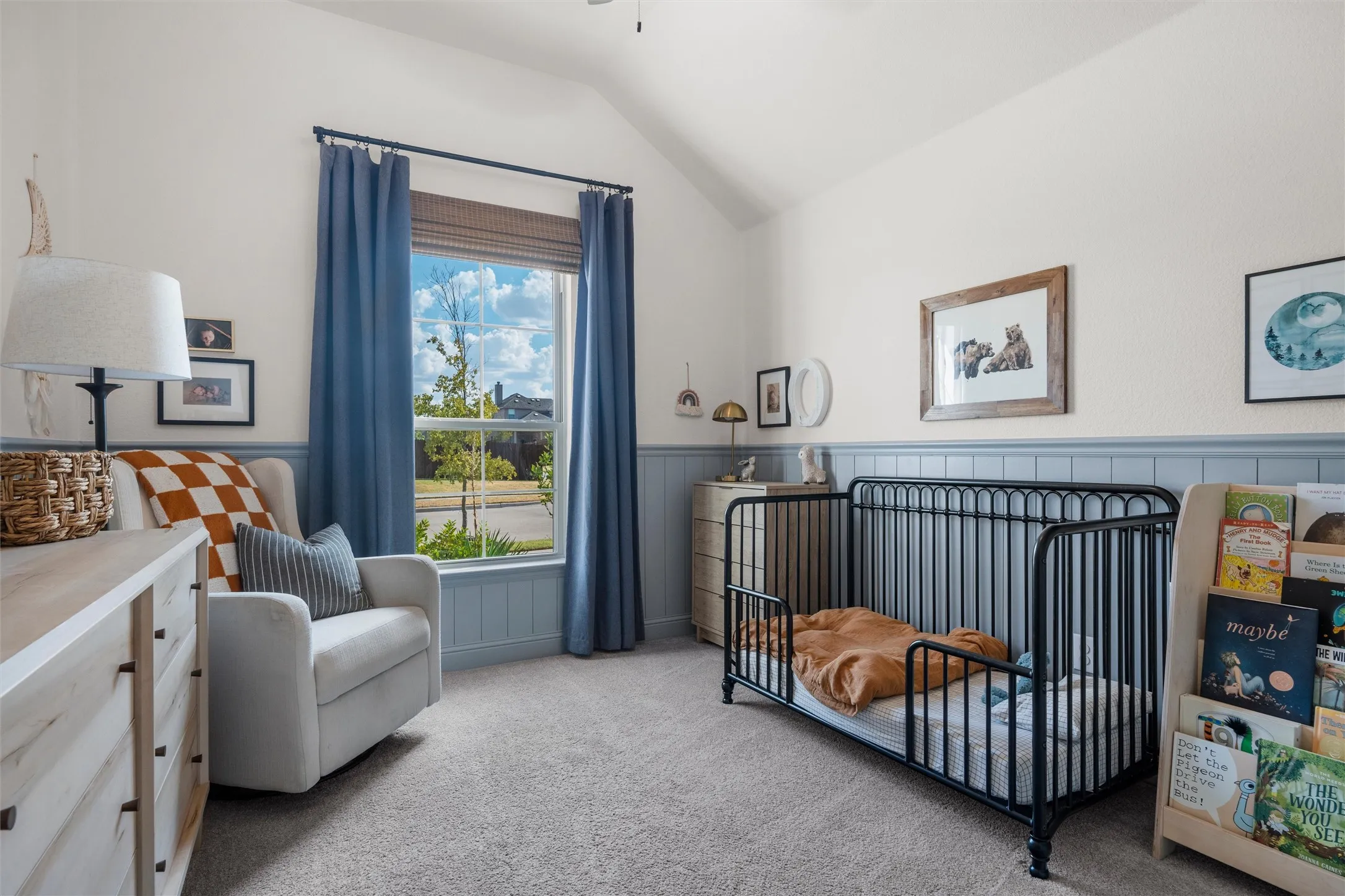 Vaulted ceiling, large window with blinds, two-tone wall treatment, ceiling fan, and carpeted flooring