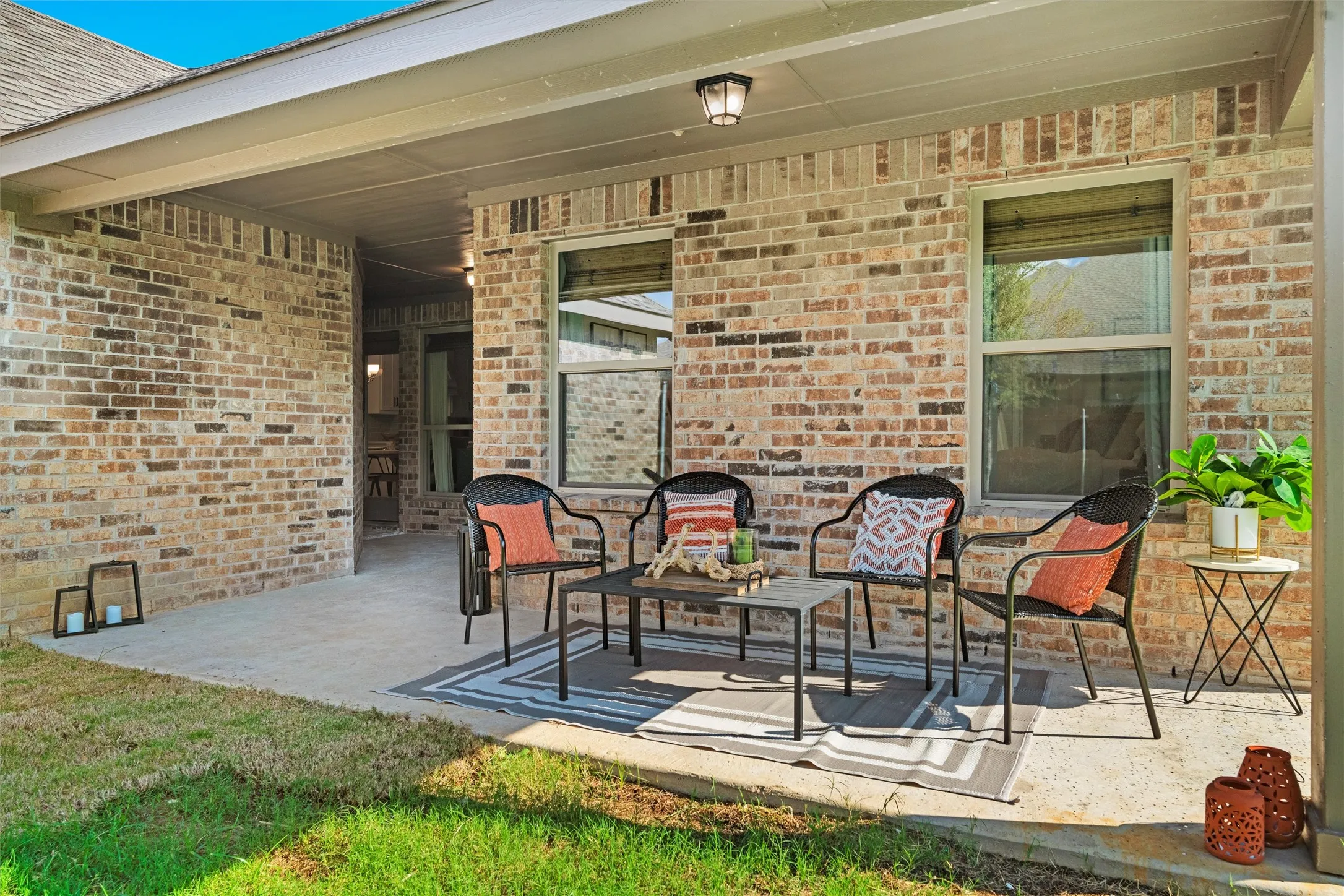 Covered concrete patio with brick exterior and dual windows