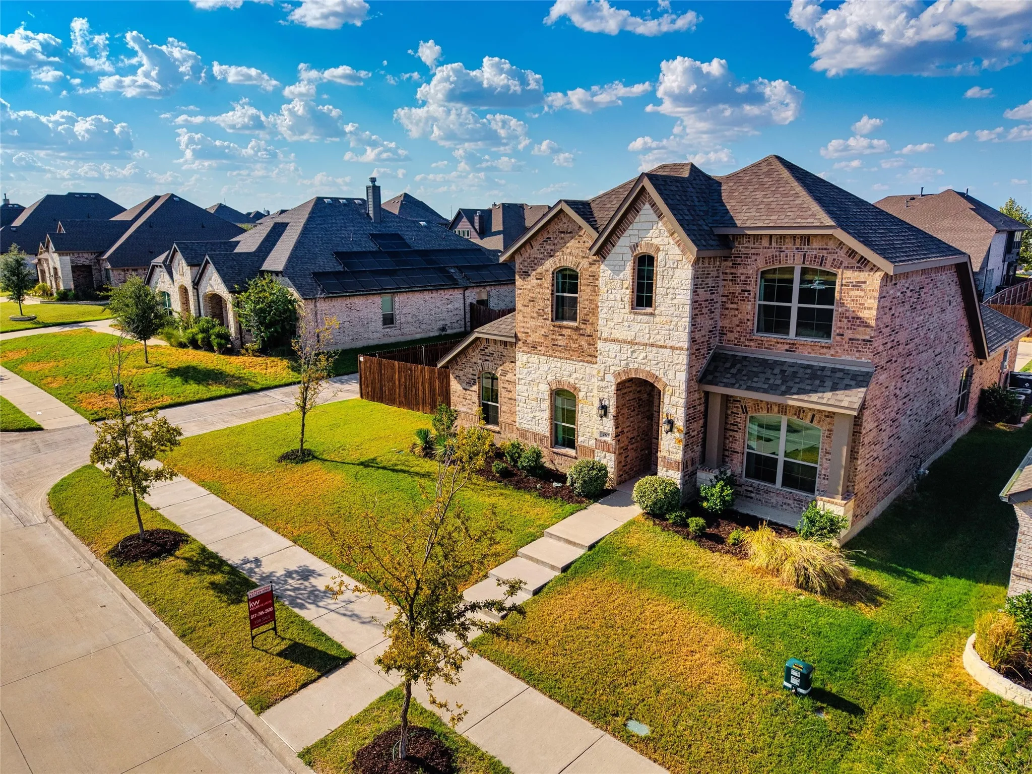 Two-story residence featuring a brick and stone exterior, arched entry, gabled rooflines, and a covered porch