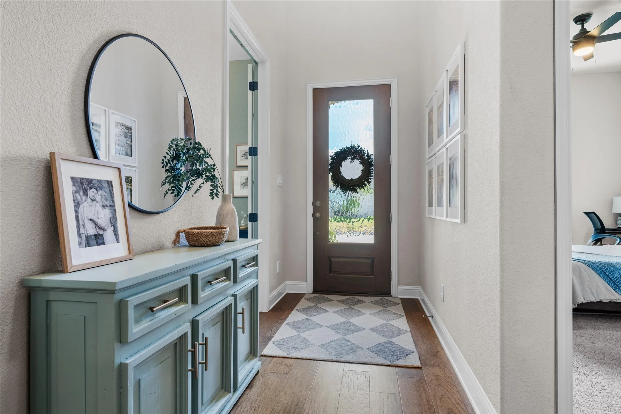 Wood-finish flooring extending from the entry, leading to a front door with a translucent glass panel