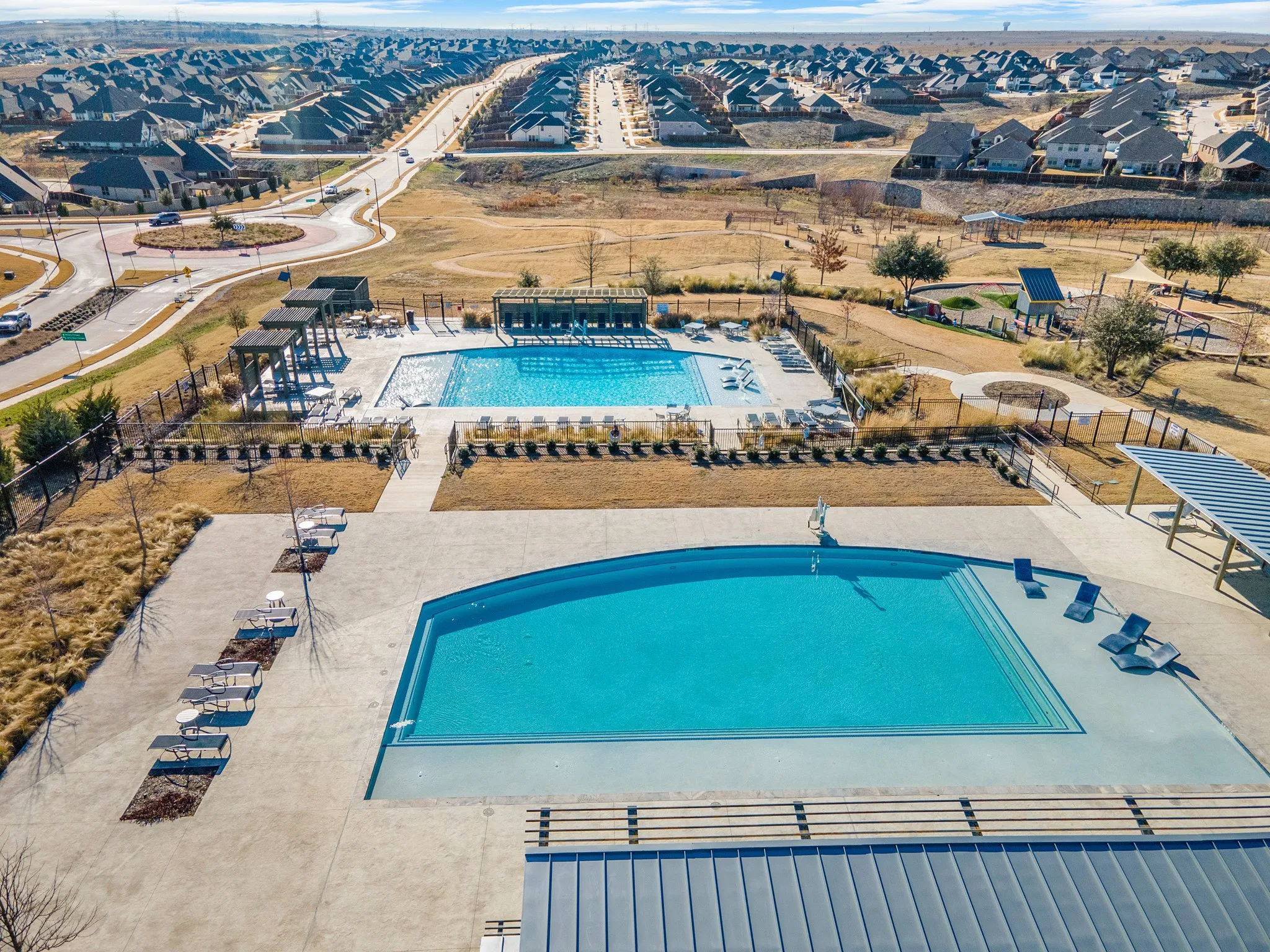 Dual resort-style swimming pools, expansive paved pool deck, and shaded pergola structures