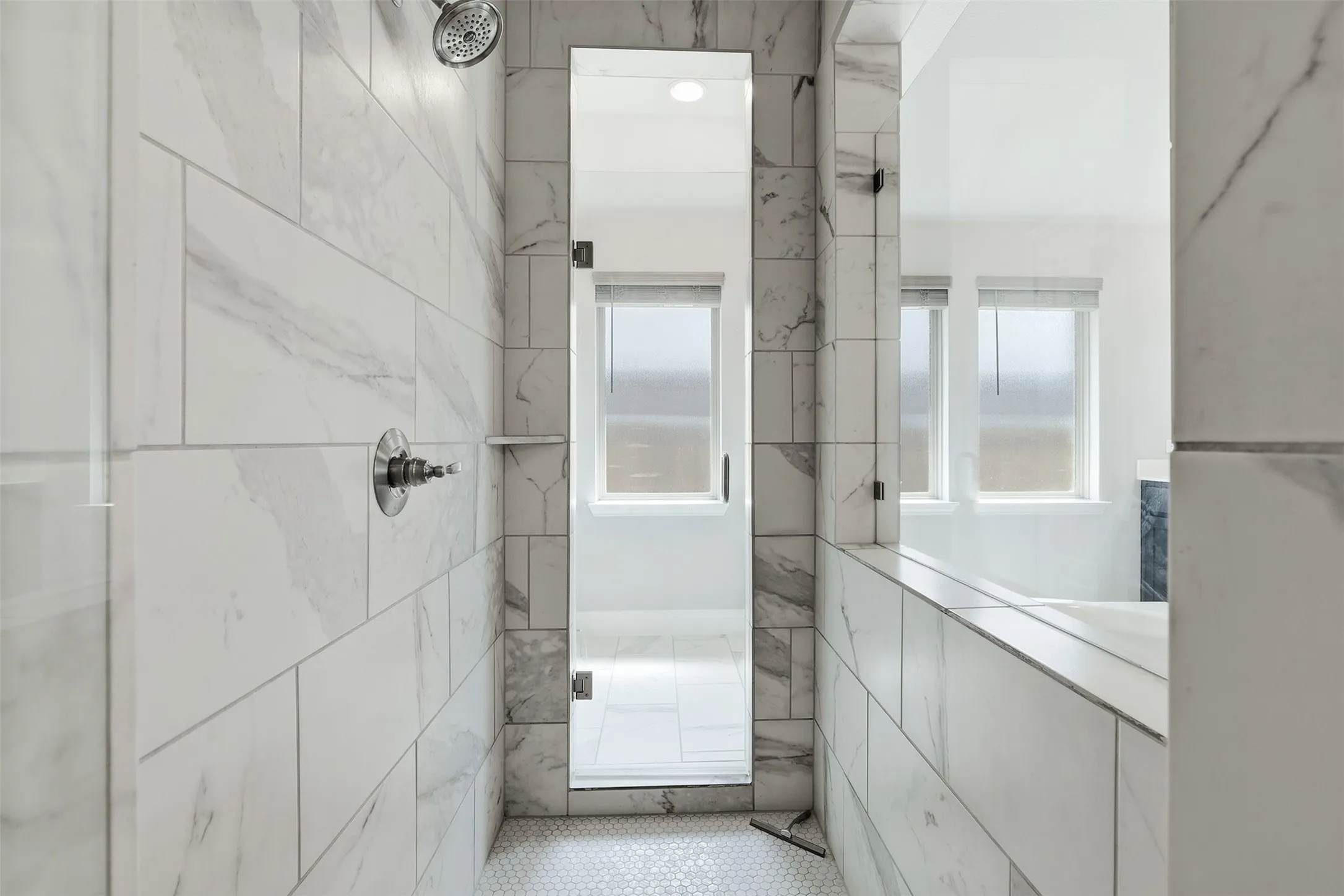 Walk-in shower featuring large format tile, a rain shower head, and a frameless glass door