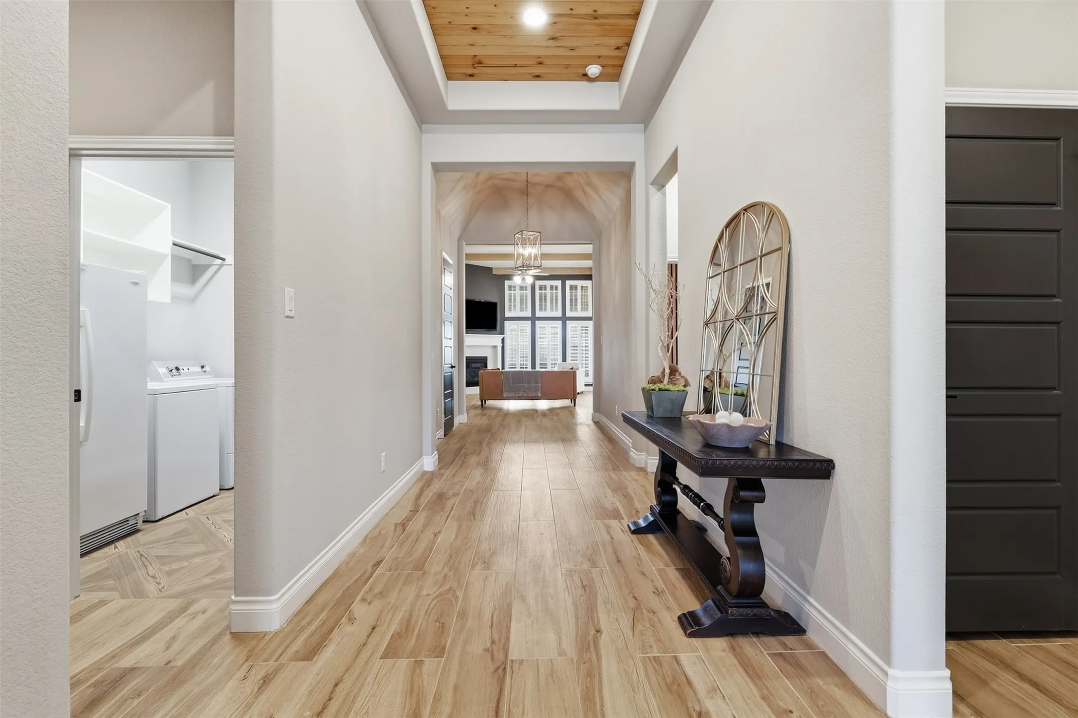 Hallway featuring wood-finish flooring, a coffered ceiling with wood paneling, and an arched entry