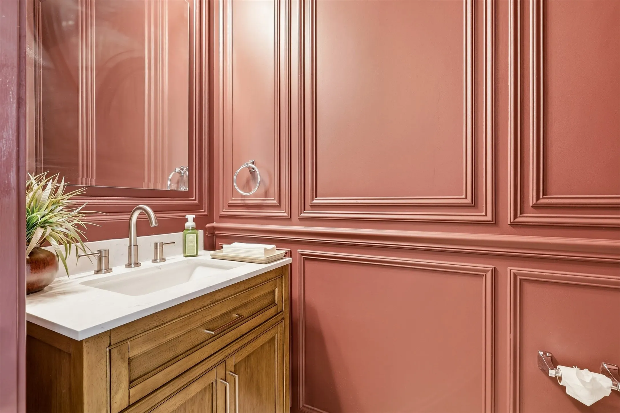 Paneling walls, wood-finish vanity, integrated sink, brushed nickel faucet, wall-mounted mirror