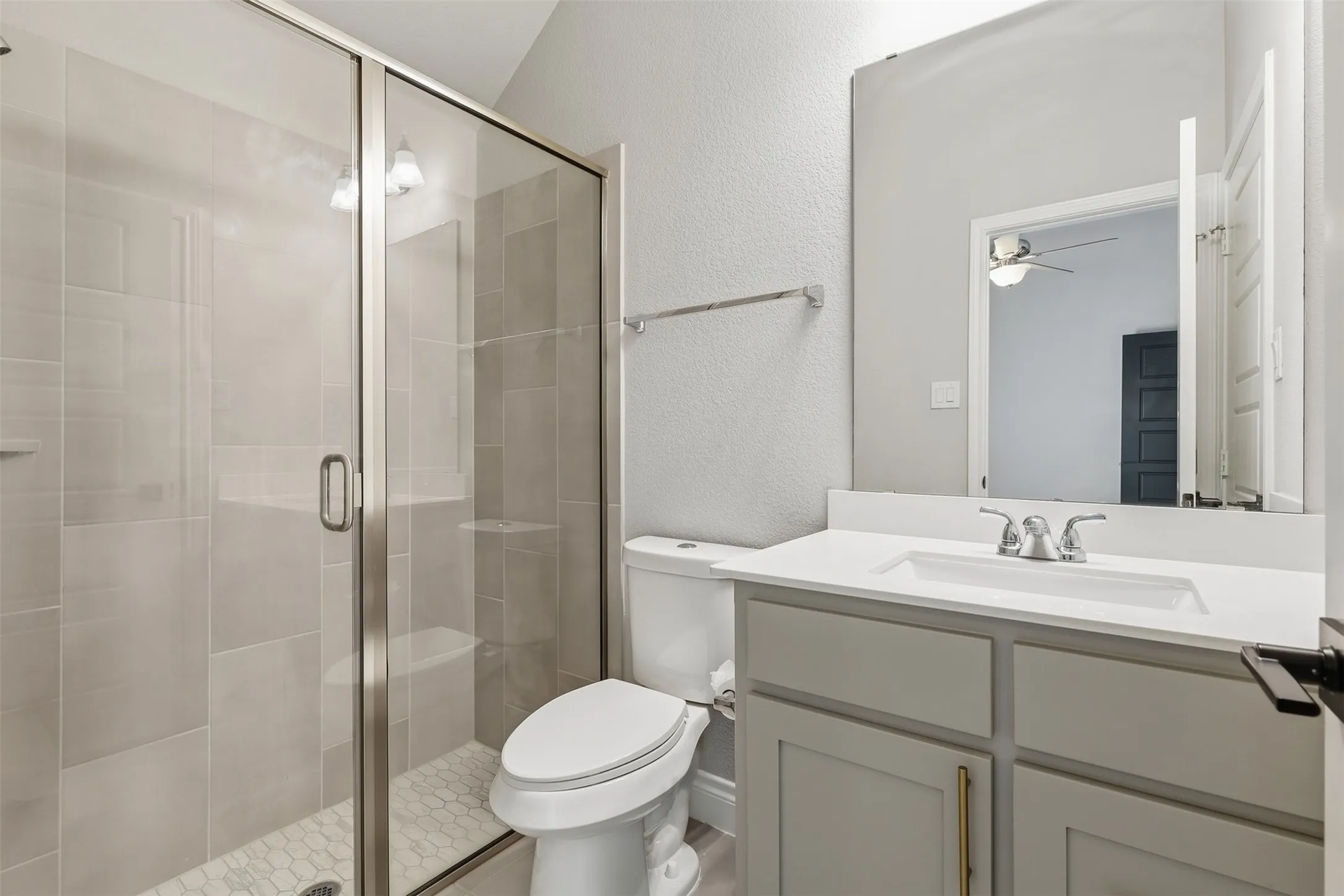 Glass-enclosed shower with subway tile surround and hexagonal tile floor