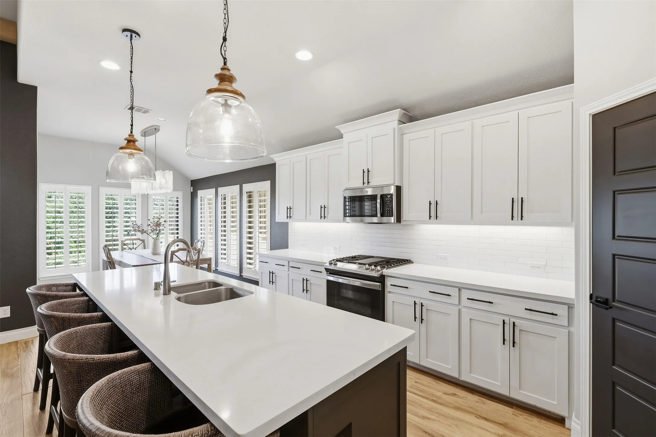 Kitchen featuring white shaker cabinetry, stainless steel appliances, white subway tile backsplash, and a large island with an undermount double-basin sink