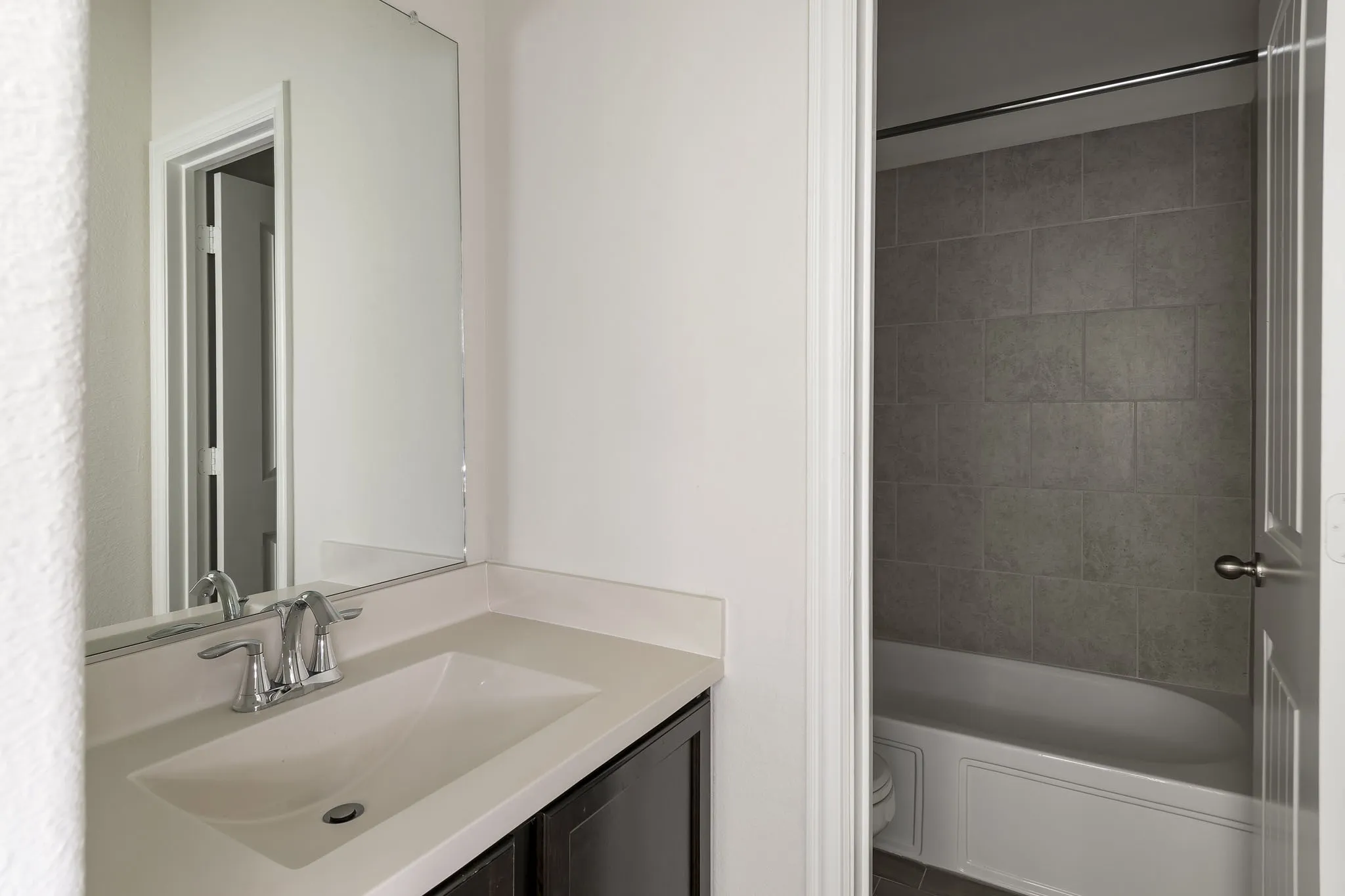 Bathroom featuring a vanity with an integrated sink, polished chrome faucet, and a large wall-mounted mirror