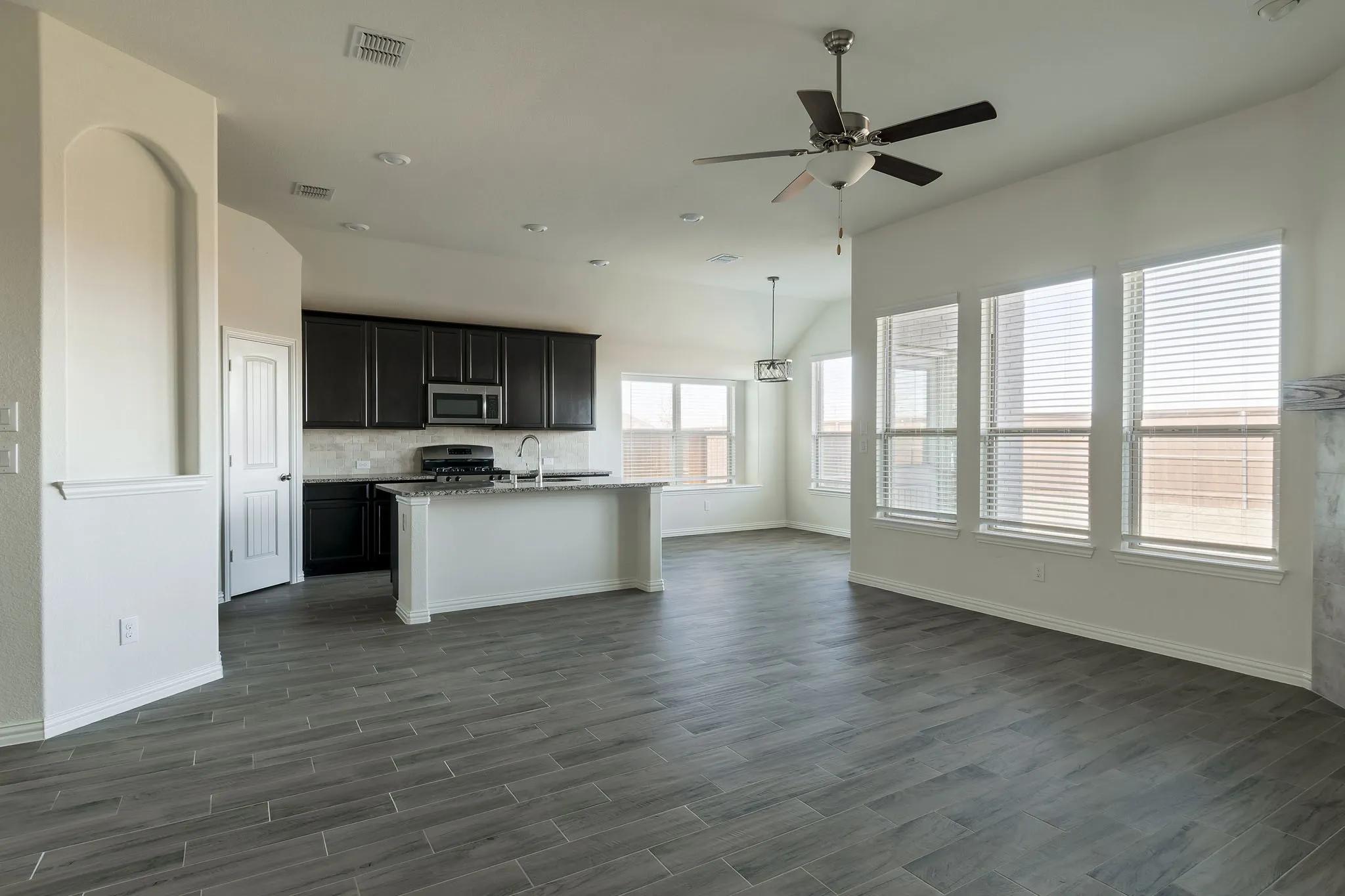 Spacious open concept design featuring wood-finish tile flooring, recessed lighting, and a modern ceiling fan