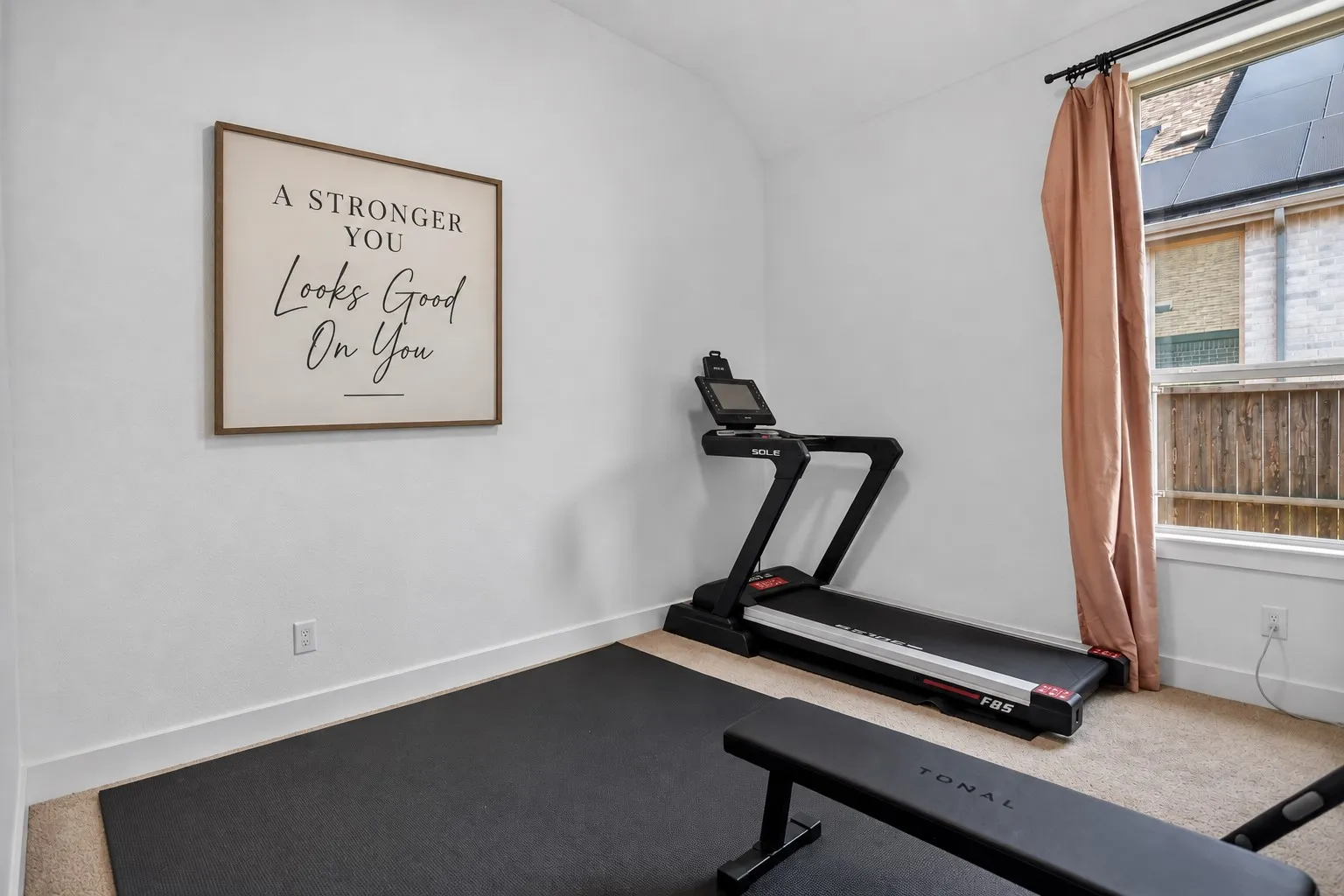 Carpeted room with a distinct sloped ceiling and a single window featuring a black curtain rod