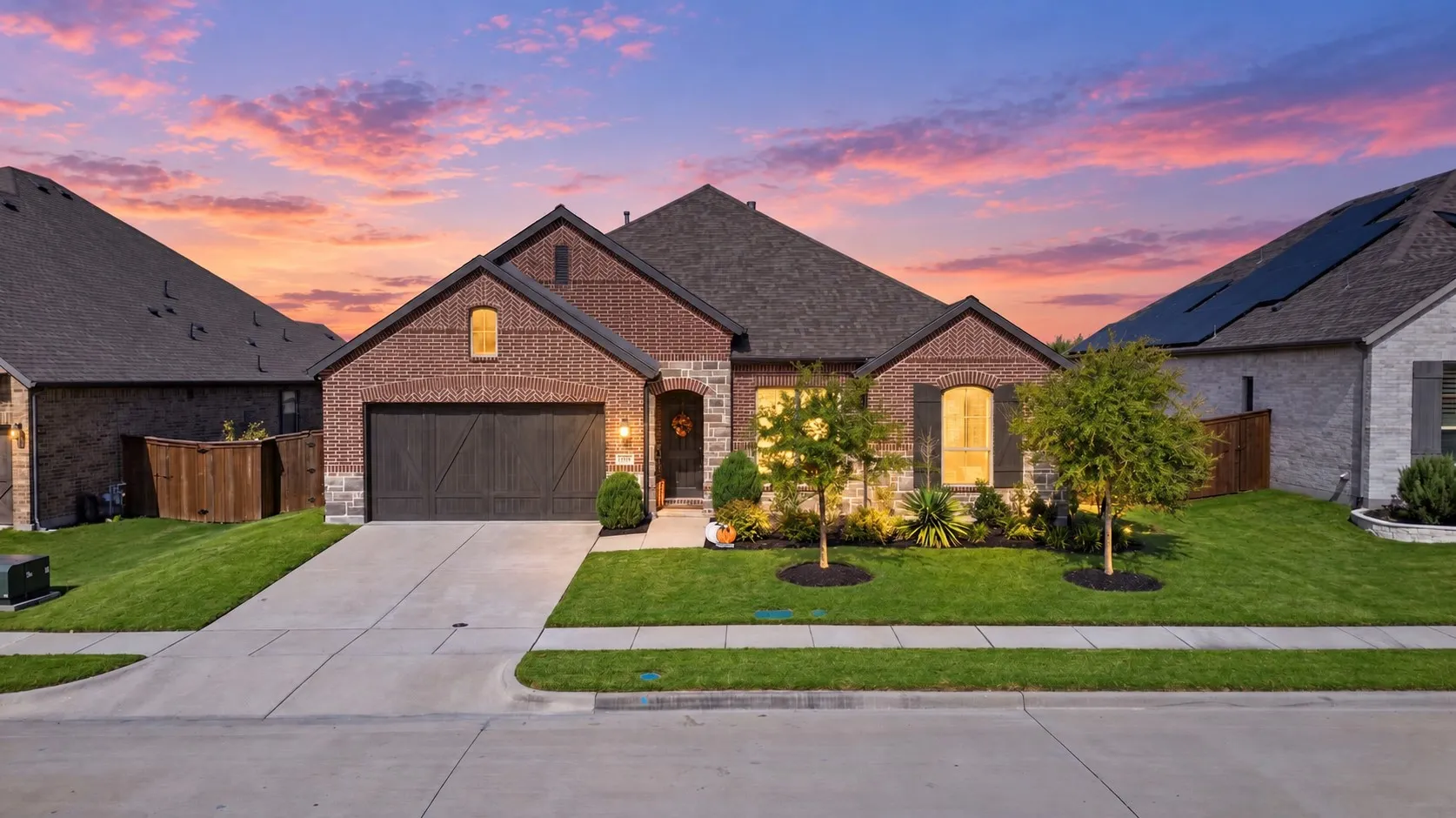 Brick and stone exterior with architectural shingles, arched windows, and a panel-style garage door