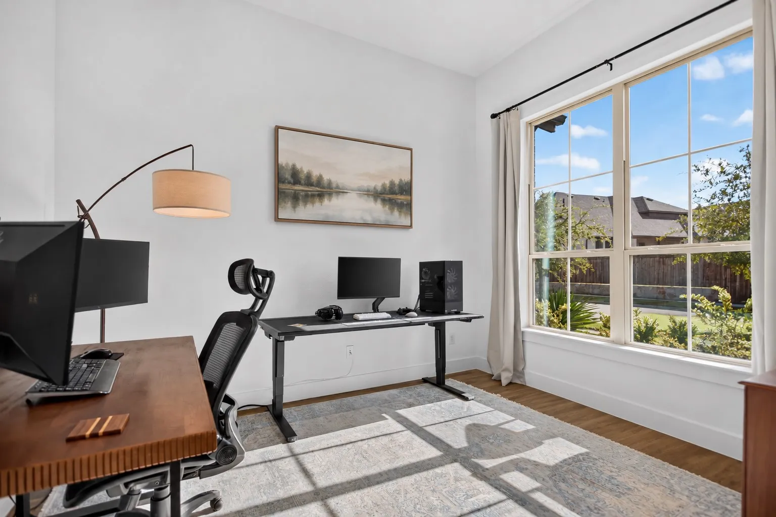 Spacious room with wood-finish flooring, a large multi-pane window, and white walls