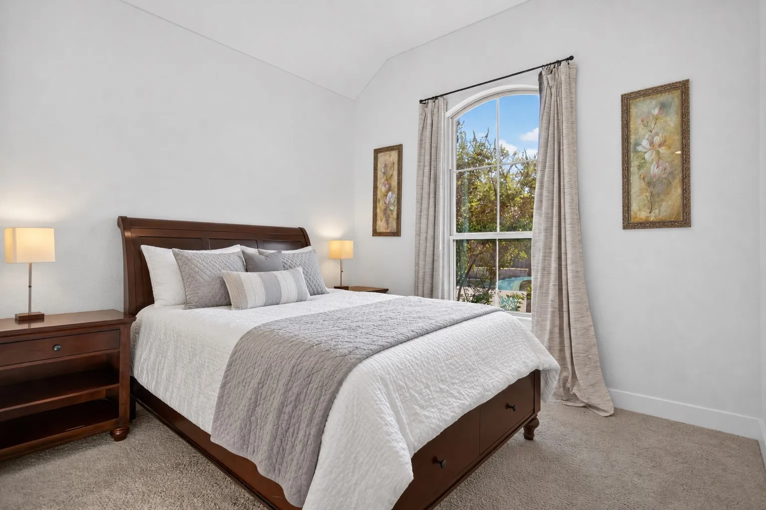 Arched window with exterior tree line, vaulted ceiling, and carpeted flooring