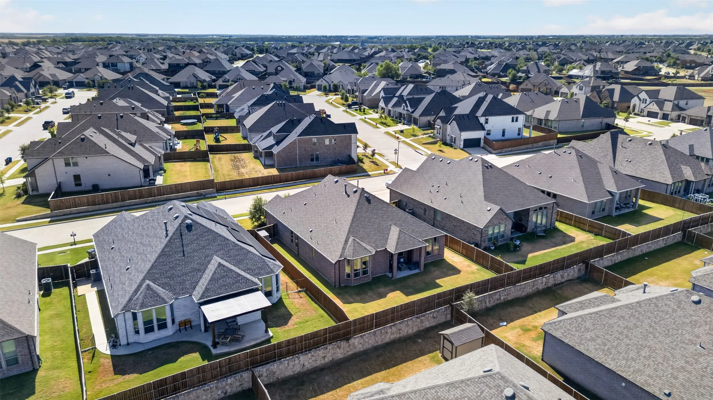 Expansive residential development featuring numerous single-family homes with pitched roofs, individual fenced yards, and concrete driveways