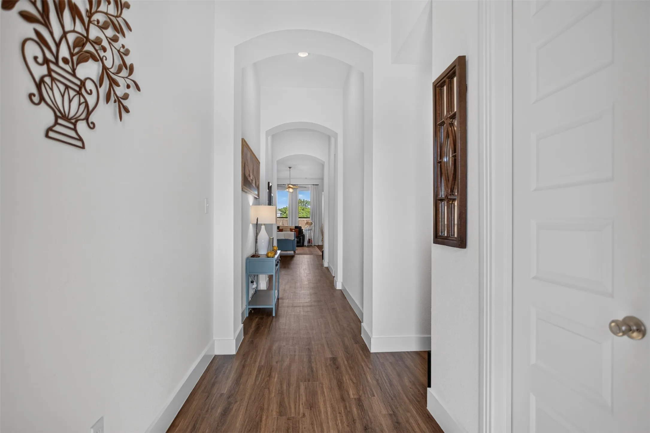 Hallway featuring wood-finish flooring, arched doorways, white trim, and recessed lighting