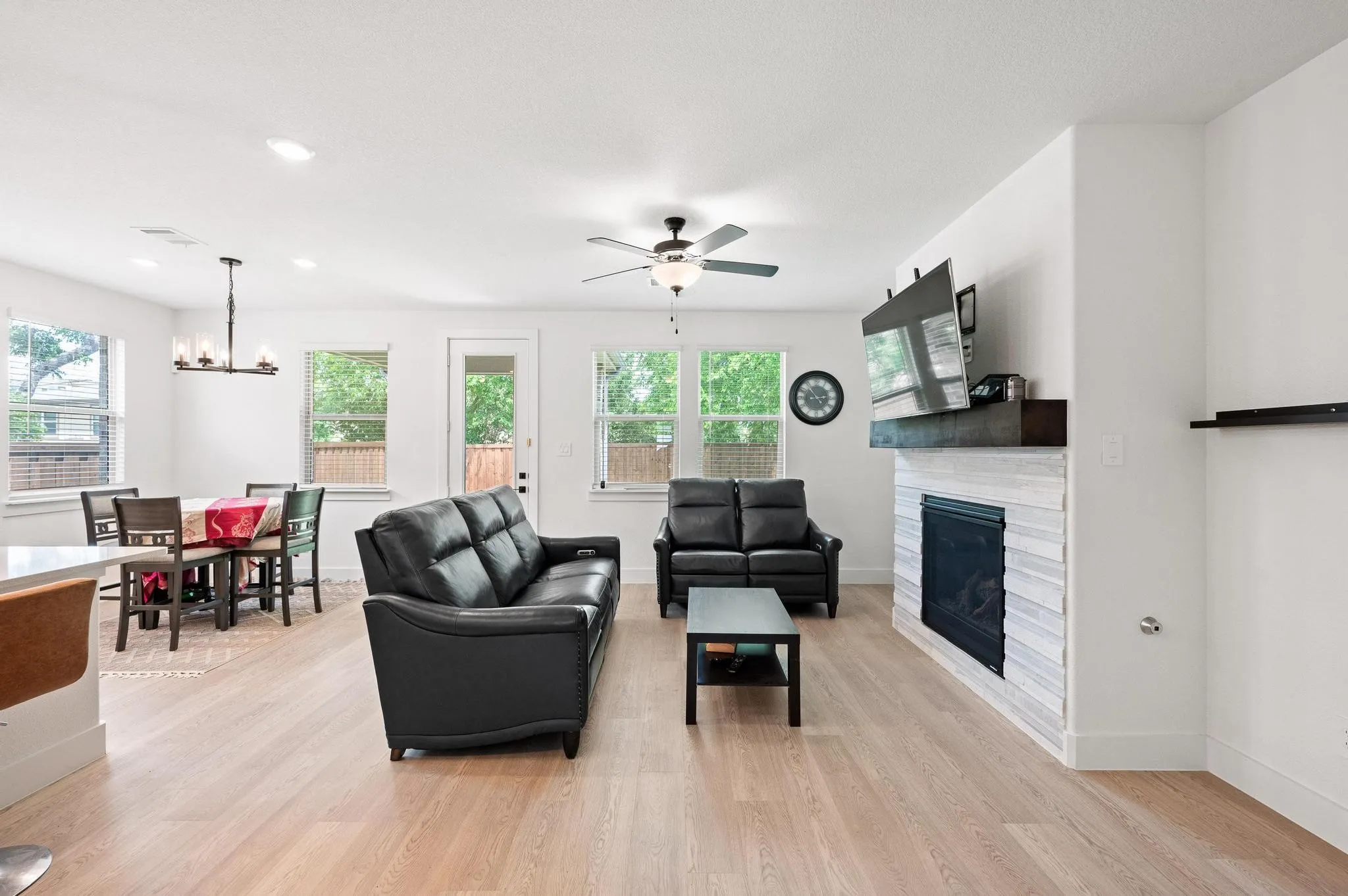 Open-concept living space with light wood-finish flooring, a contemporary ceiling fan, and recessed lighting