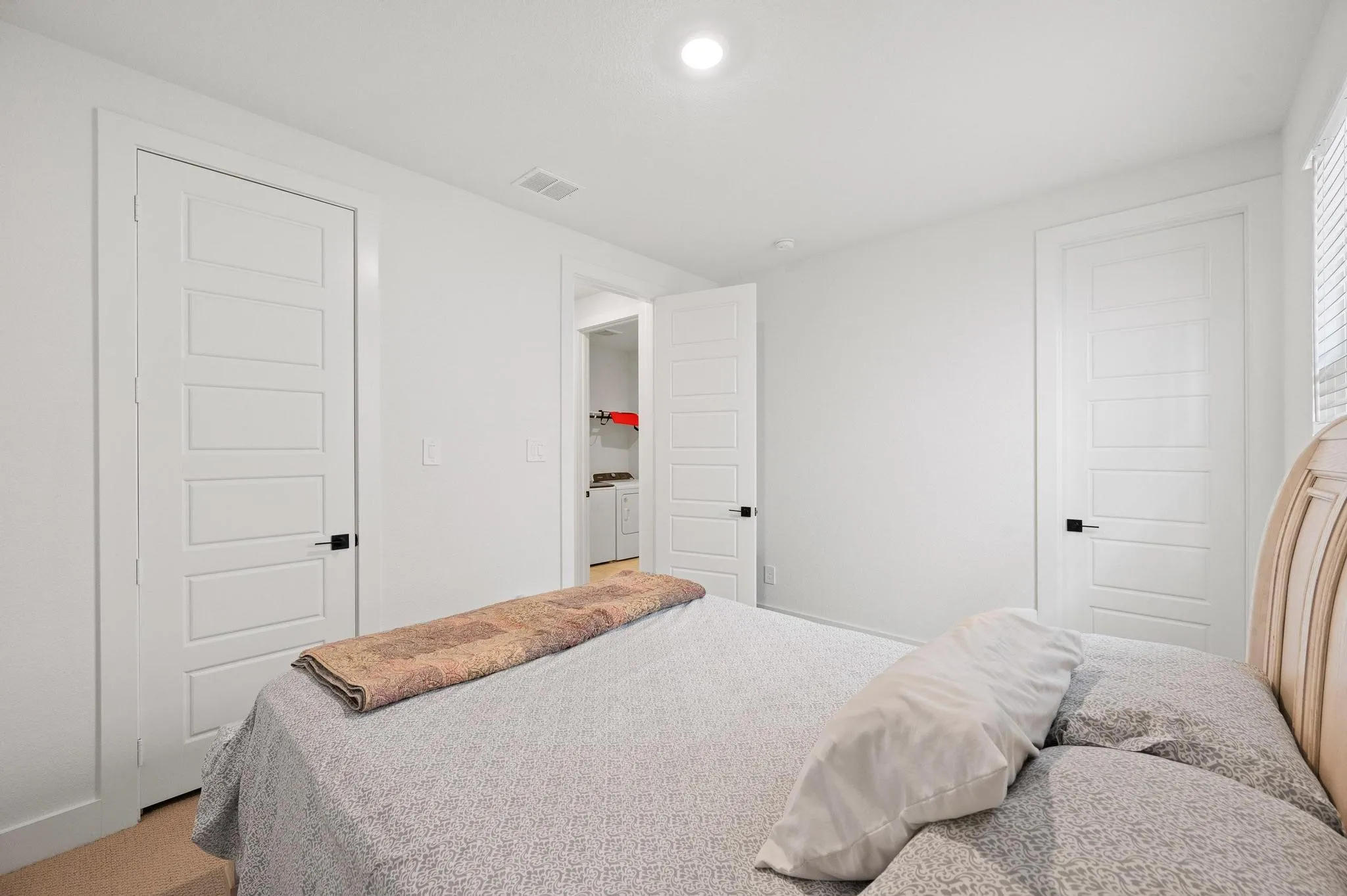 White interior doors with black hardware, white walls, recessed ceiling lighting, and carpet flooring