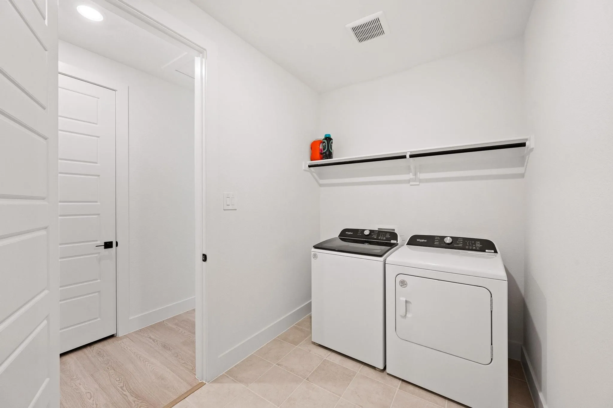 Dedicated laundry space featuring a built-in shelf, light-toned tile flooring, and recessed lighting