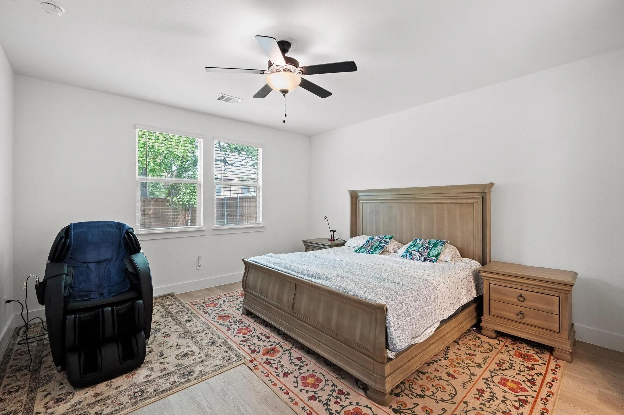 Recessed ceiling lighting, two large windows, ceiling fan with light fixture, light wood-finish flooring