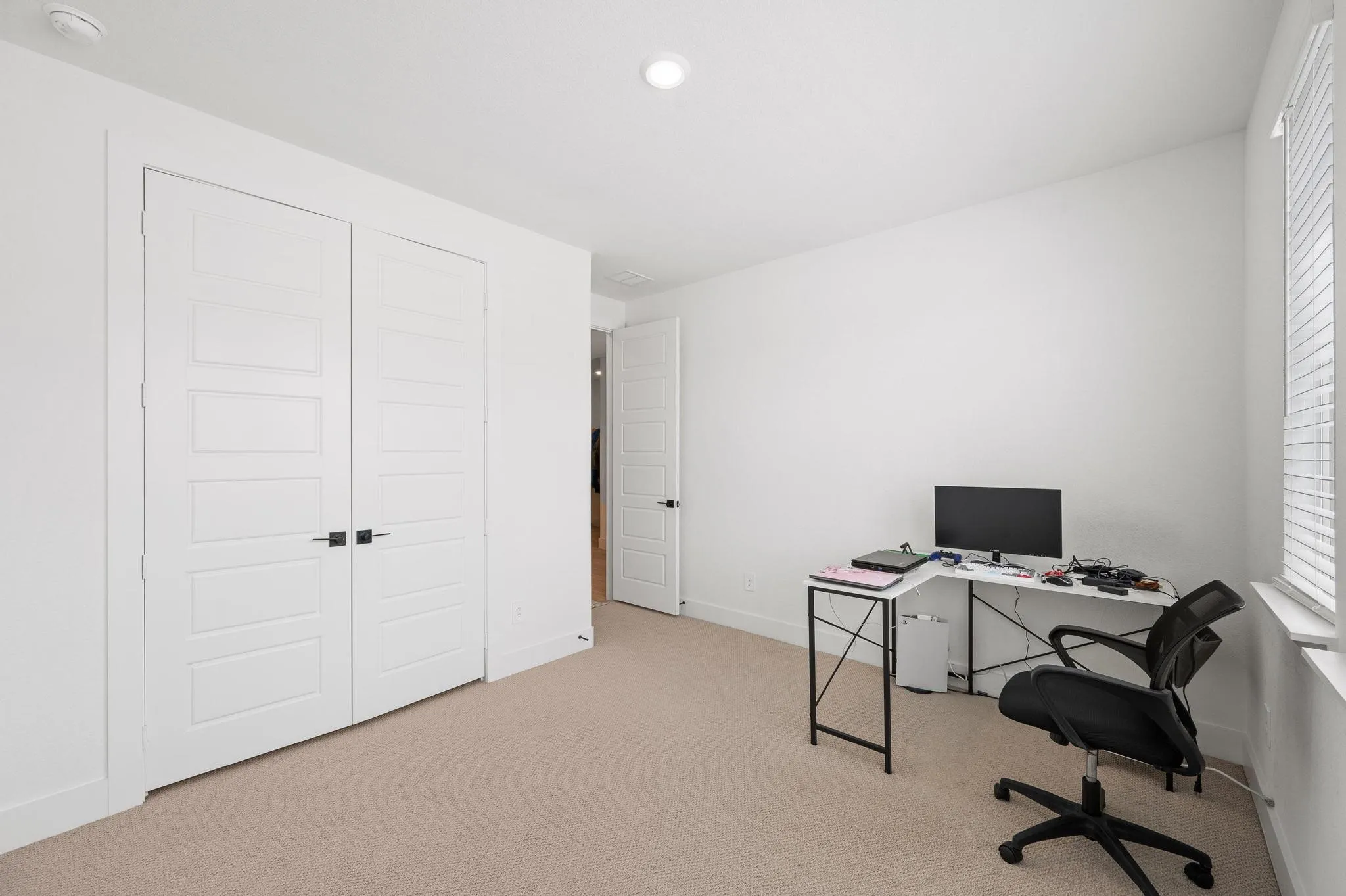 Neutral-toned carpeting, white walls, and a window with blinds