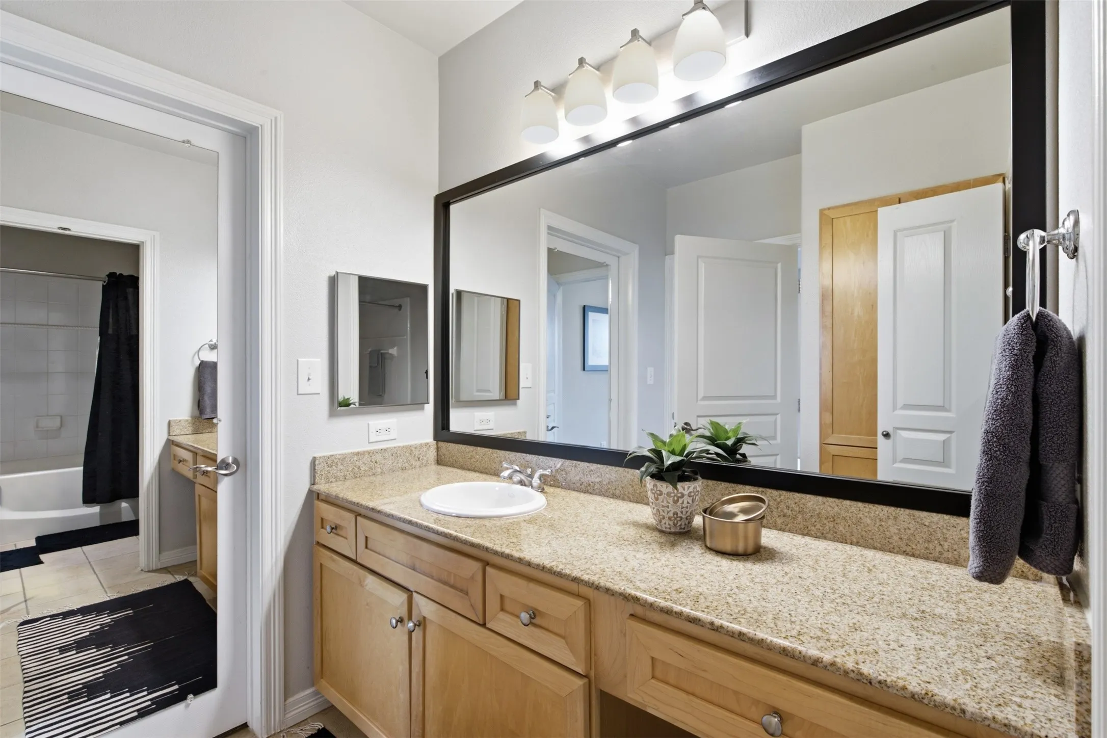 Spacious vanity with light-toned cabinetry, light-colored countertop, and a large framed mirror