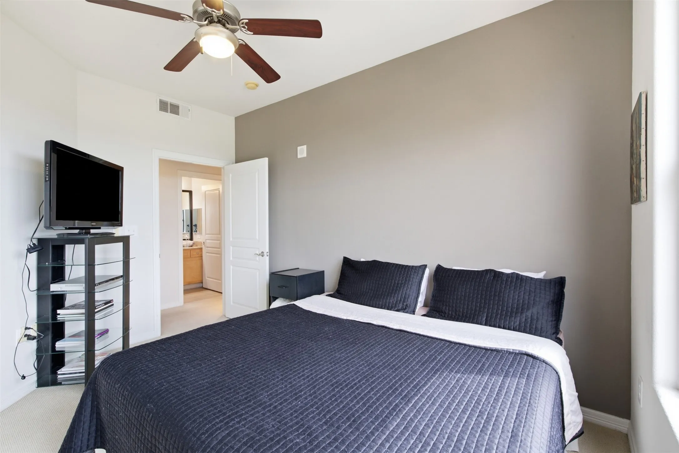 Room featuring a ceiling fan with integrated lighting, a contrasting accent wall, and carpet flooring