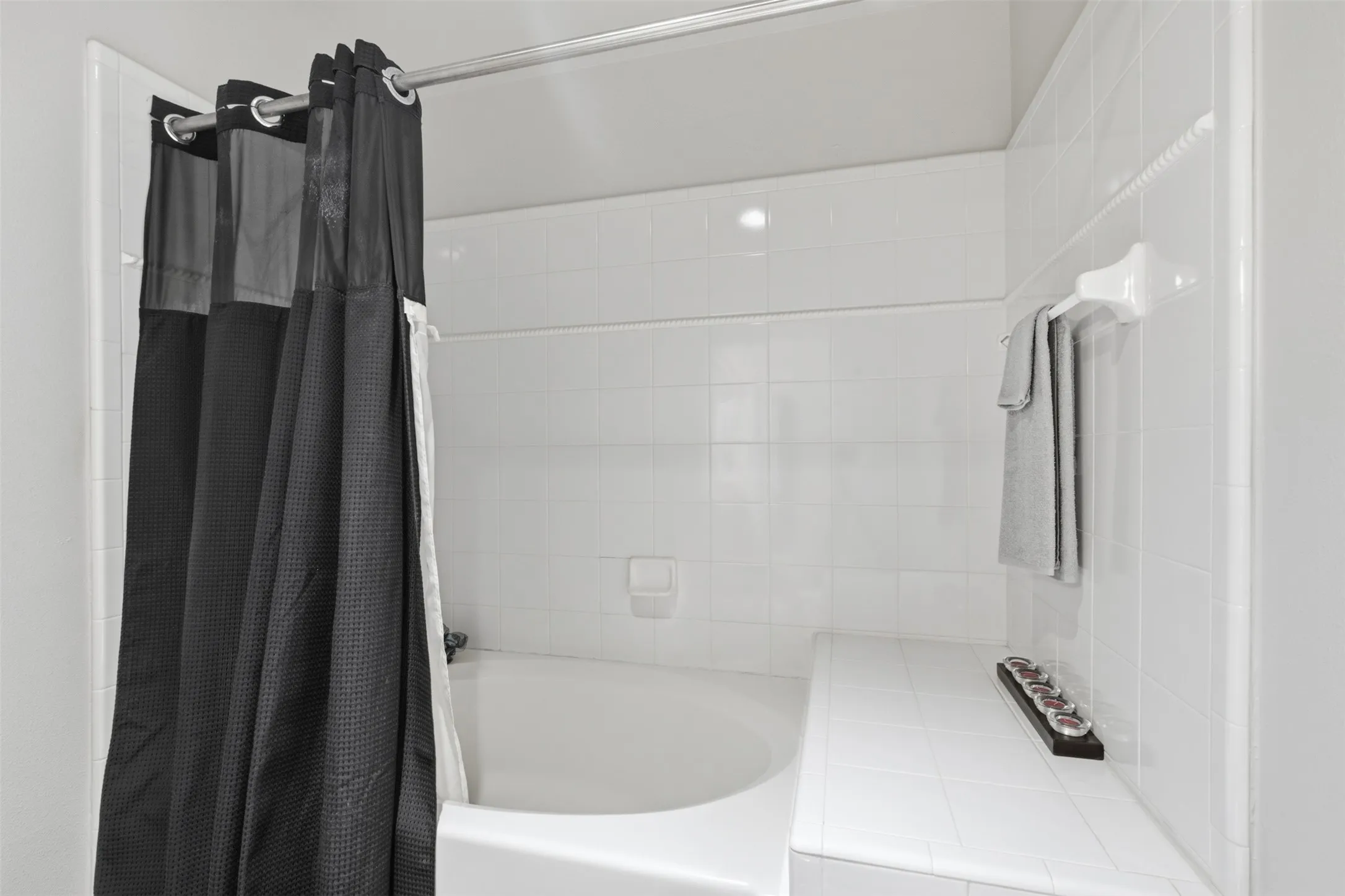 Integrated bathtub with white tile surround and a tiled ledge