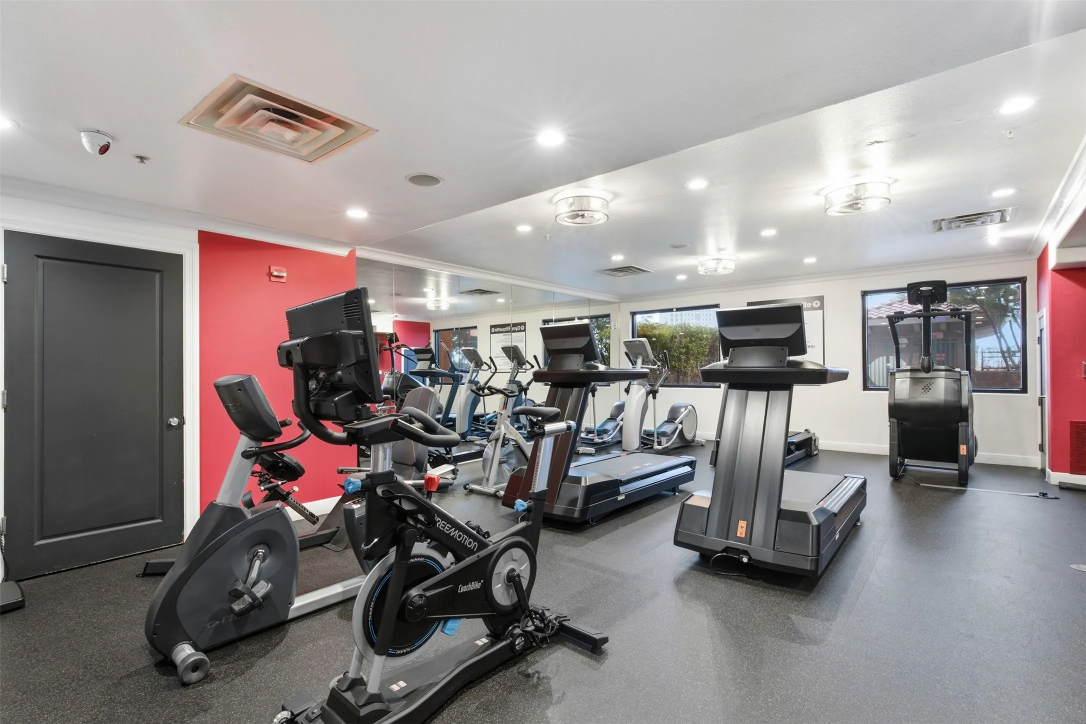 Fitness facility featuring resilient flooring, recessed lighting, wall-mounted mirrors, and multiple windows