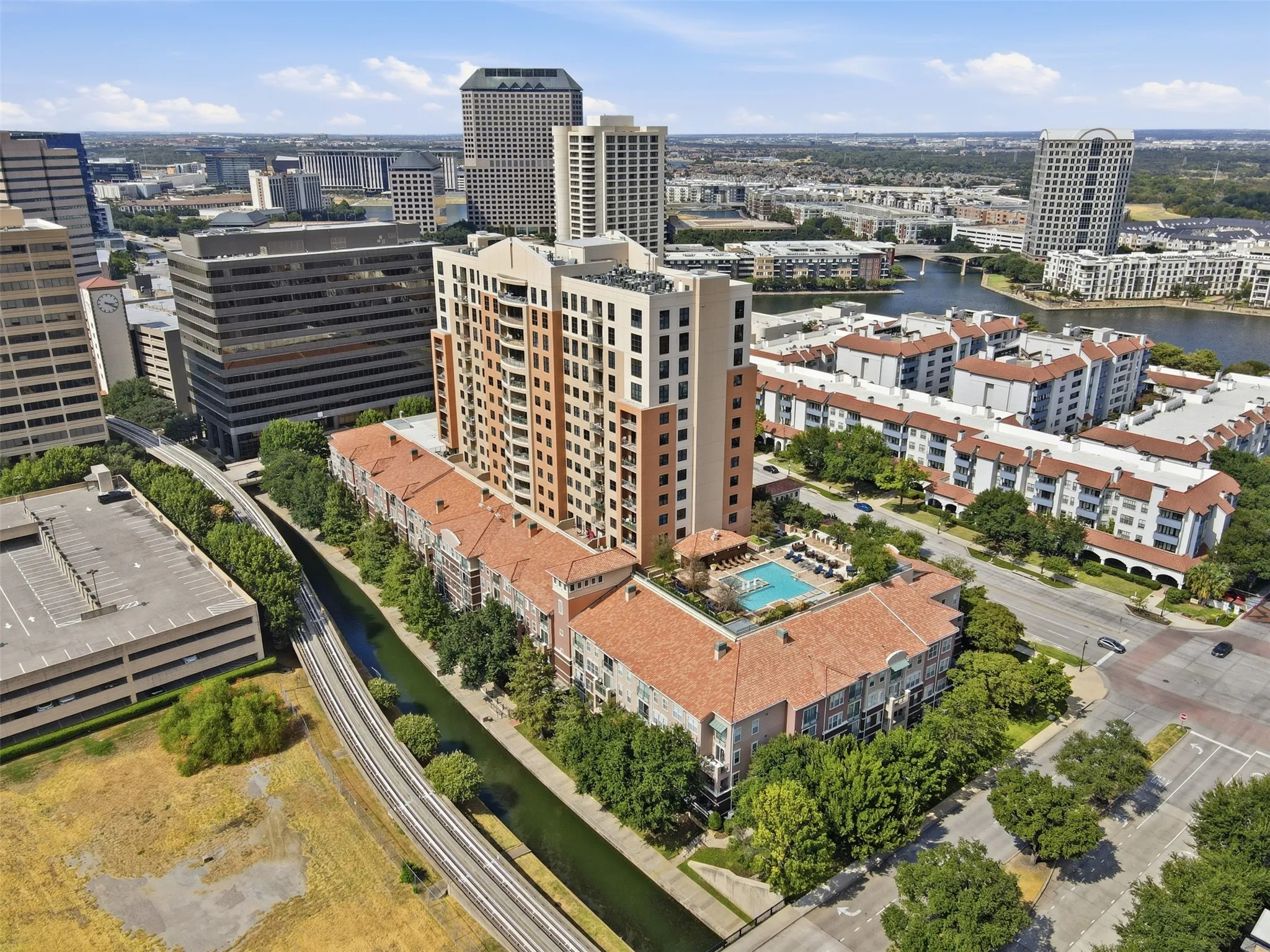 High-rise residential building with a tiled roof lower level, outdoor swimming pool, and surrounding urban landscape