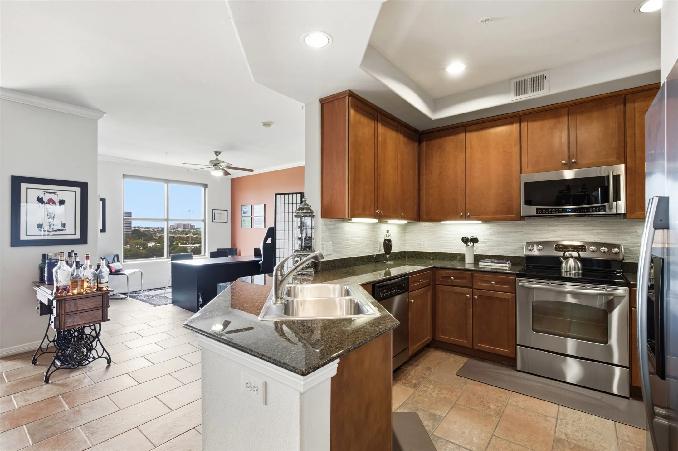 Kitchen featuring wood cabinetry, stainless steel appliances, granite countertops, and a tile​​‌​​​​‌​​‌‌​‌‌​​​‌‌​‌​‌​‌​​​‌​​ backsplash