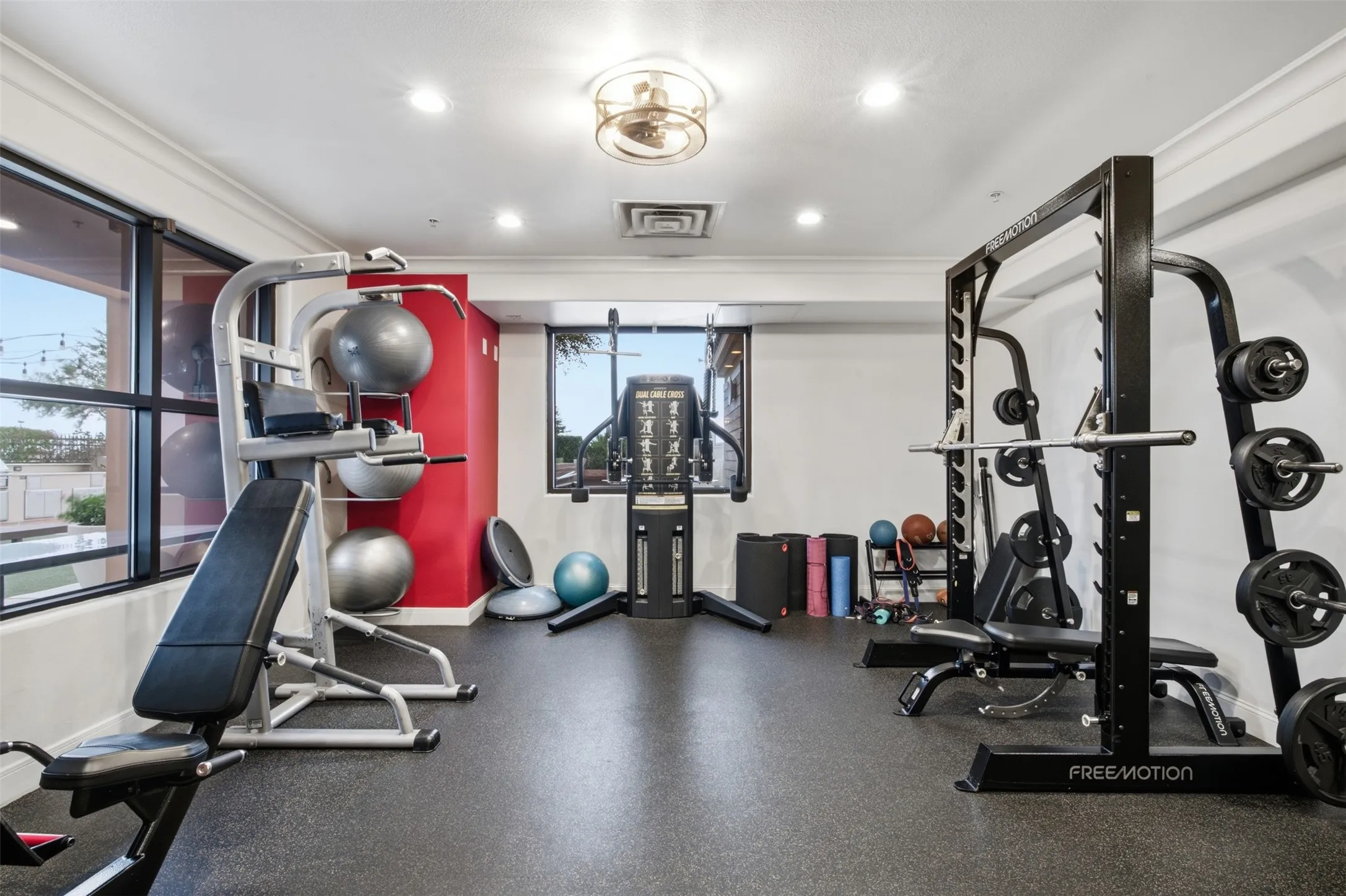 Fitness facility featuring resilient flooring, recessed lighting, wall-mounted mirrors, and multiple windows
