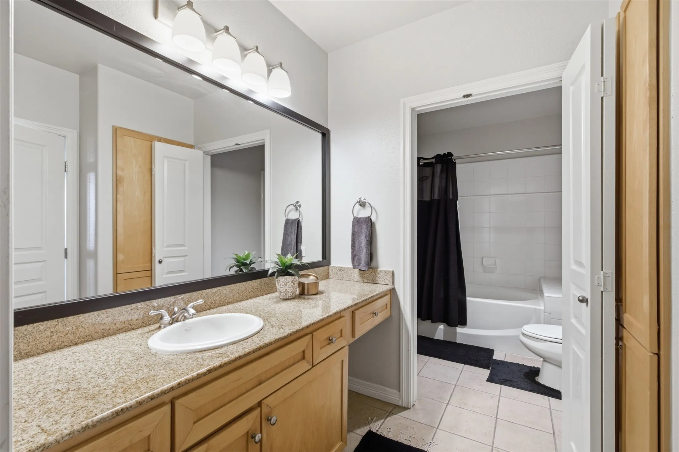 Spacious bathroom vanity featuring a granite countertop, undermount sink, and wood-finish cabinetry