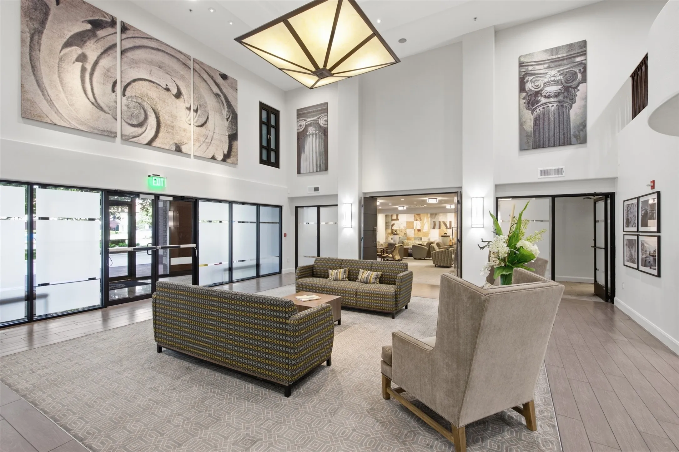 Open-concept reception area featuring high ceilings, wood-finish flooring, and large glass panel walls