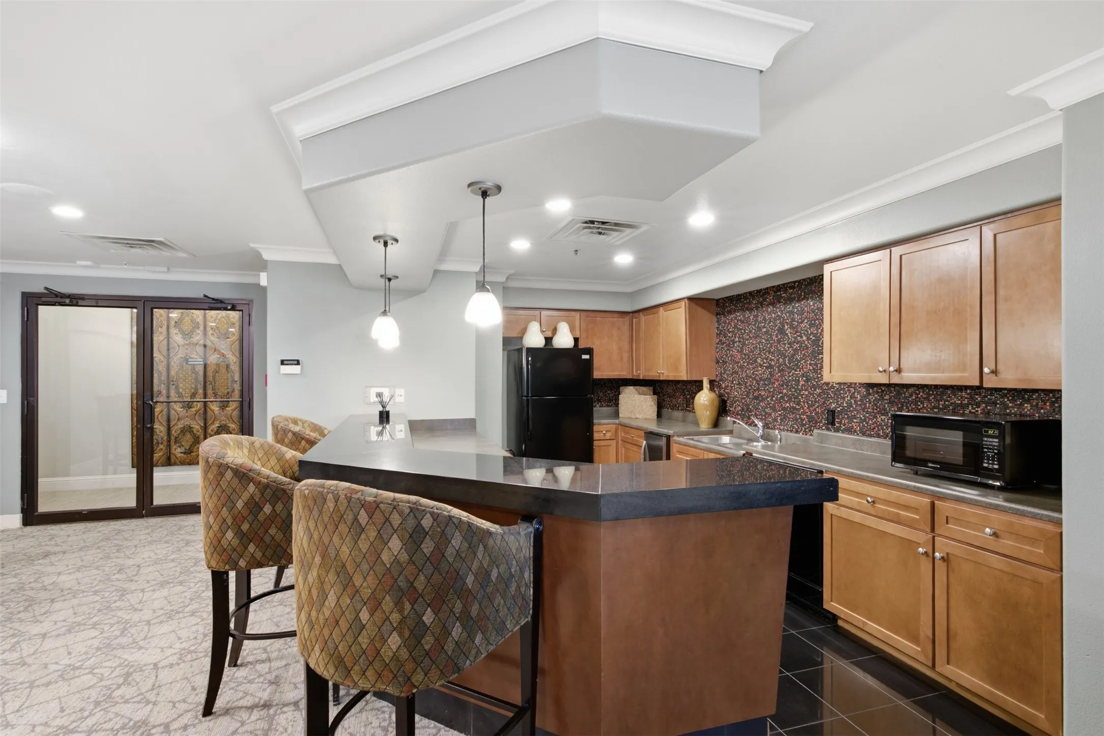 Kitchenette featuring wood cabinetry, black appliances, a dark countertop, and a mosaic tile backsplash