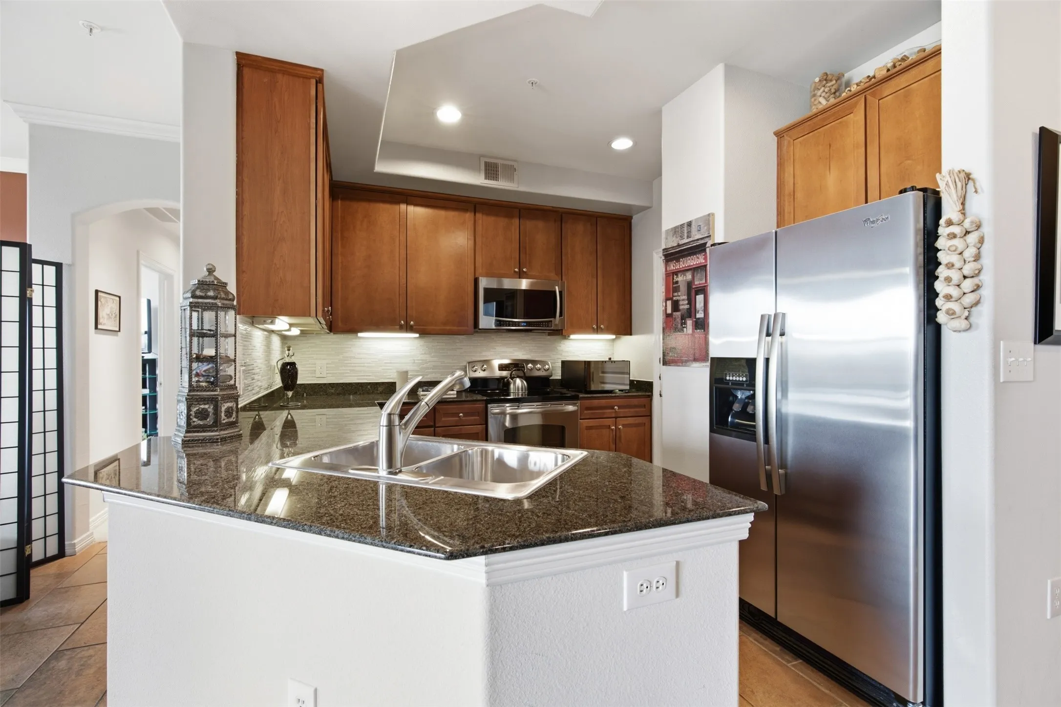 Kitchen featuring a dual basin sink, stainless steel appliances, wood cabinetry, granite countertops, and recessed lighting