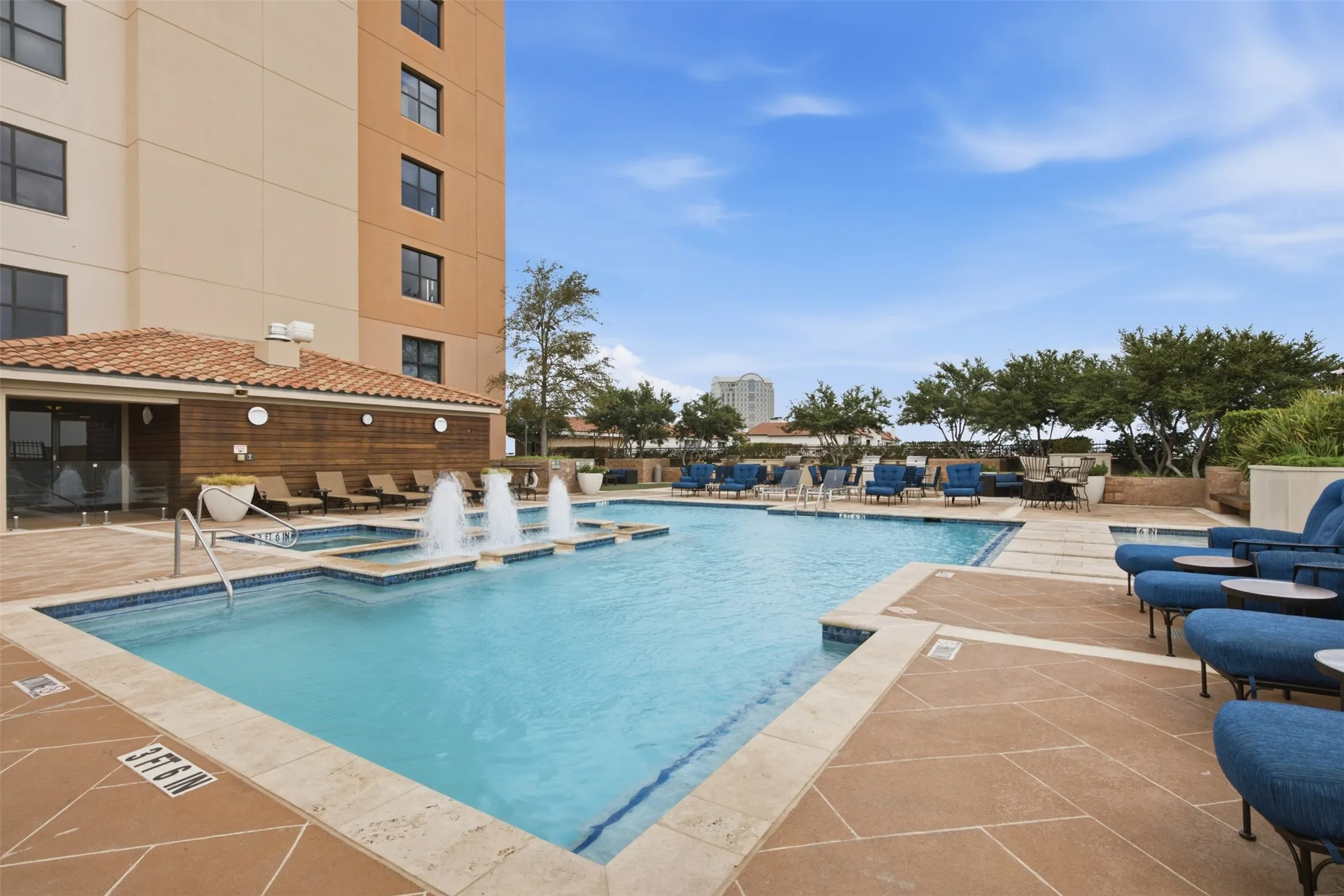 Spacious outdoor pool deck featuring a swimming pool, integrated spa, and fountains