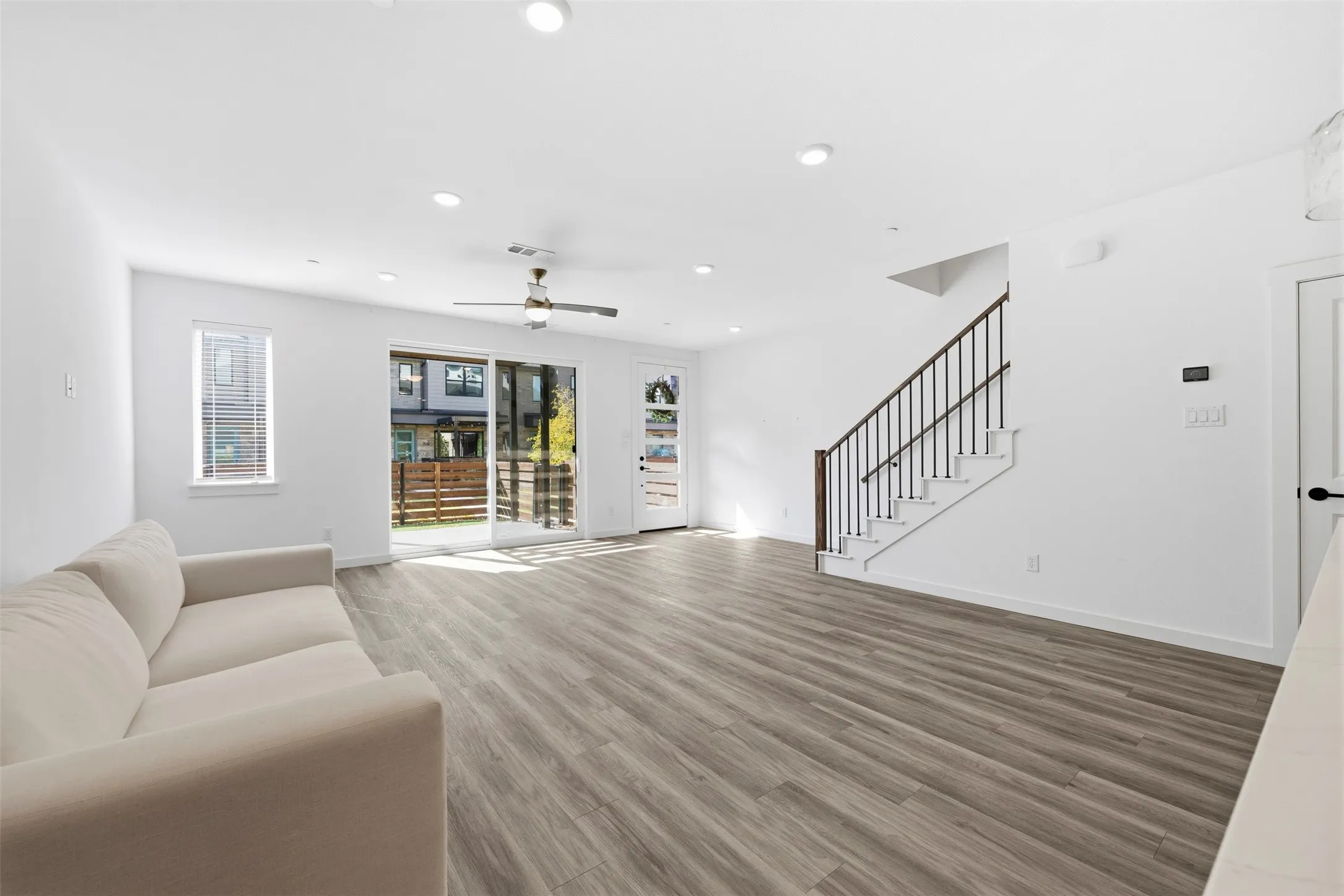 Spacious living area featuring wood-finish flooring, recessed lighting, and a ceiling fan