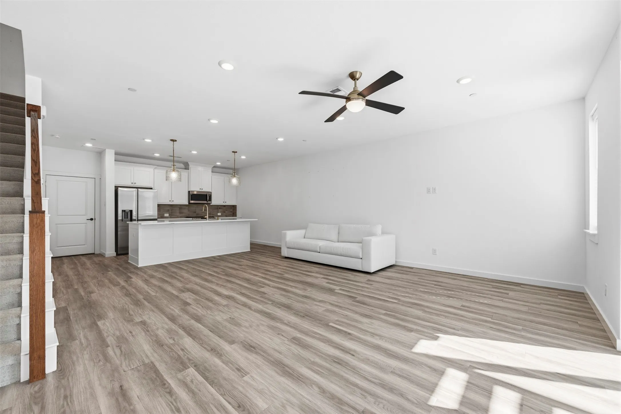 Open-concept living space featuring wood-finish flooring, recessed lighting, and a contemporary ceiling fan