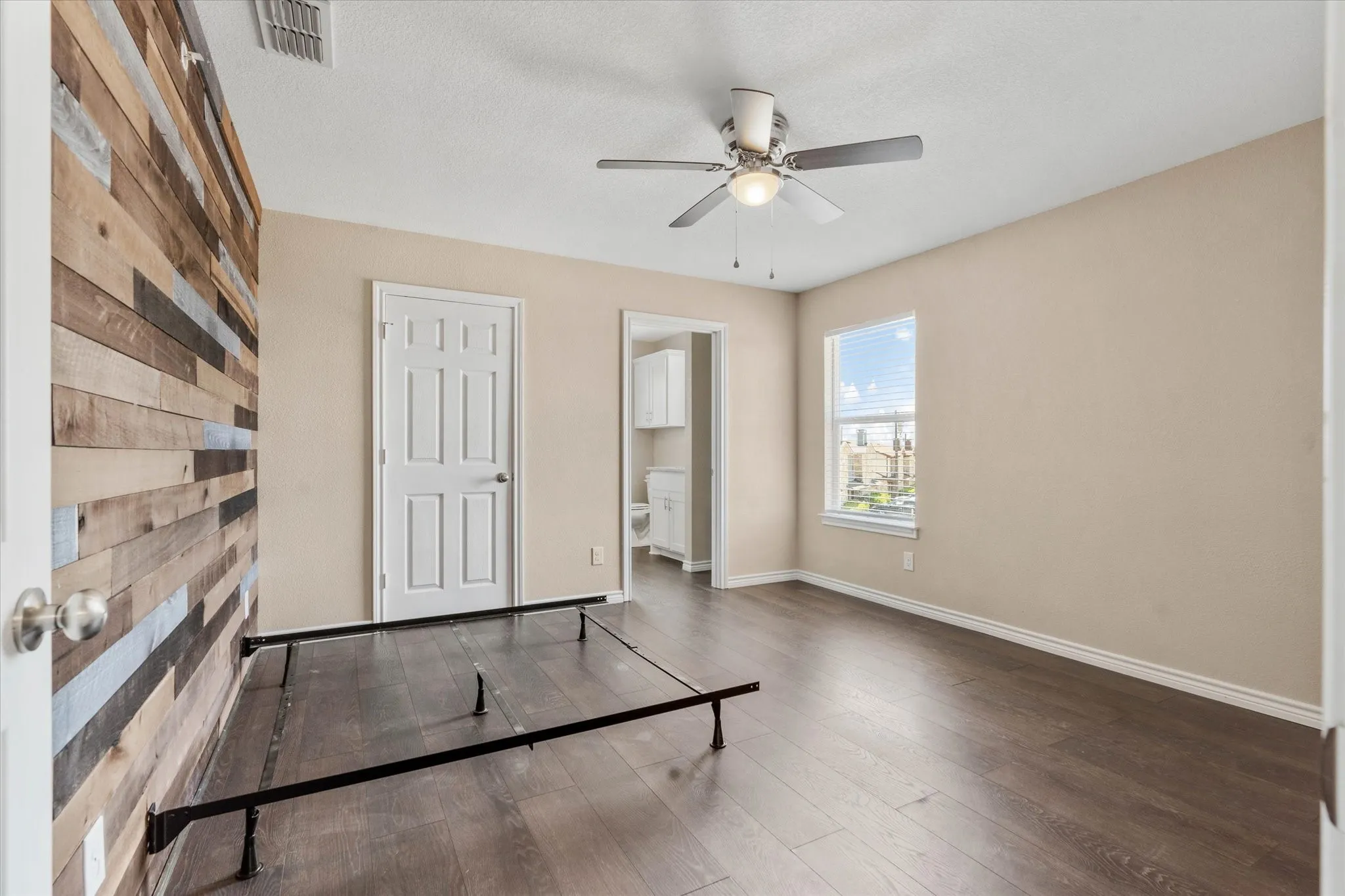 Unfurnished bedroom featuring ensuite bathroom, ceiling fan, and hardwood / wood-style floors
