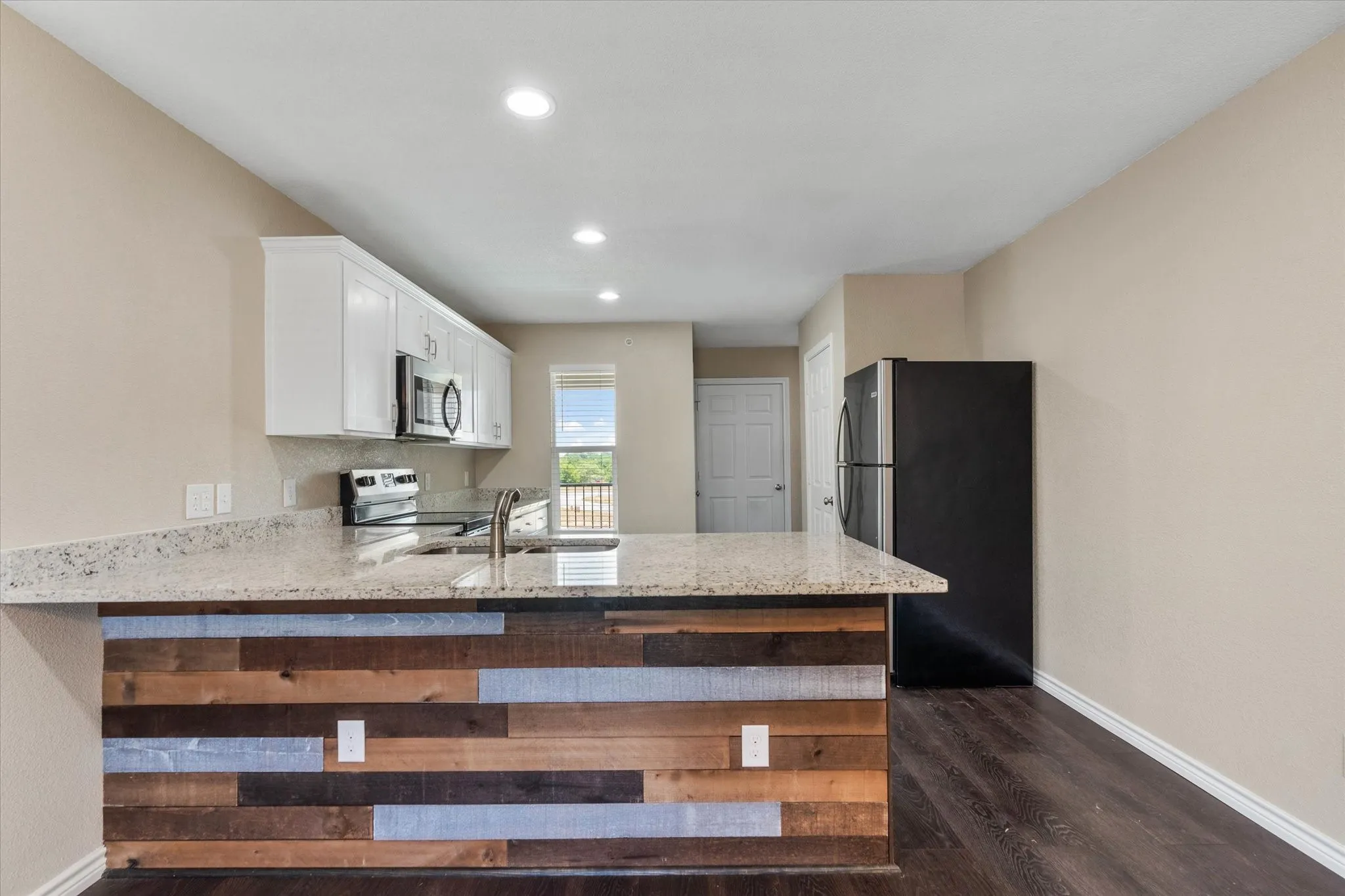 Kitchen featuring appliances with stainless steel finishes, dark hardwood / wood-style flooring, white cabinetry, and light stone counters