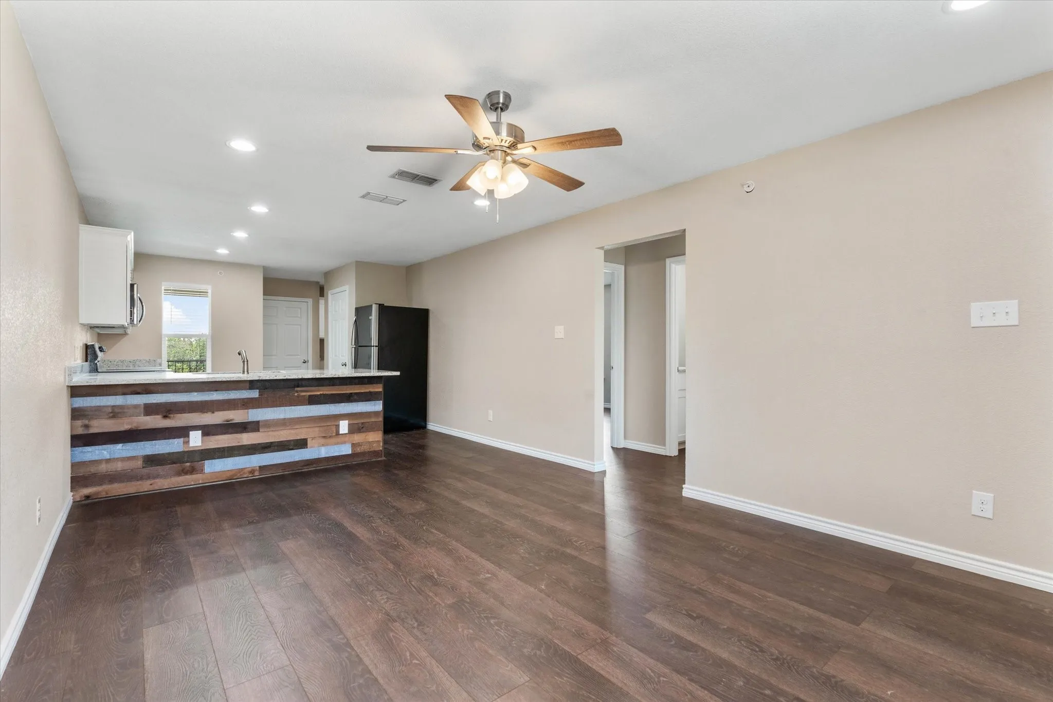 Unfurnished living room with sink, dark wood-type flooring, and ceiling fan