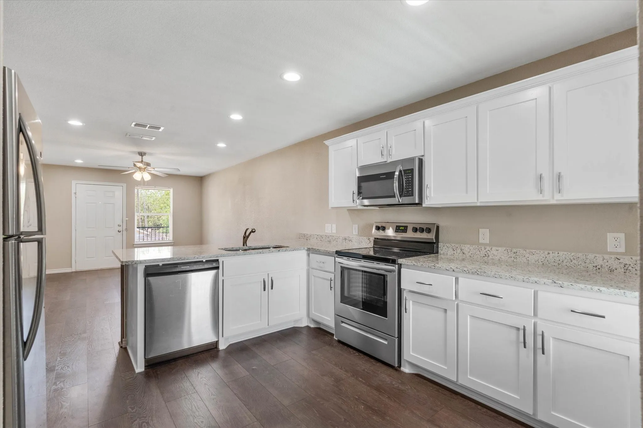 Kitchen featuring ceiling fan, stainless steel appliances, white cabinets, dark hardwood / wood-style floors, and kitchen peninsula
