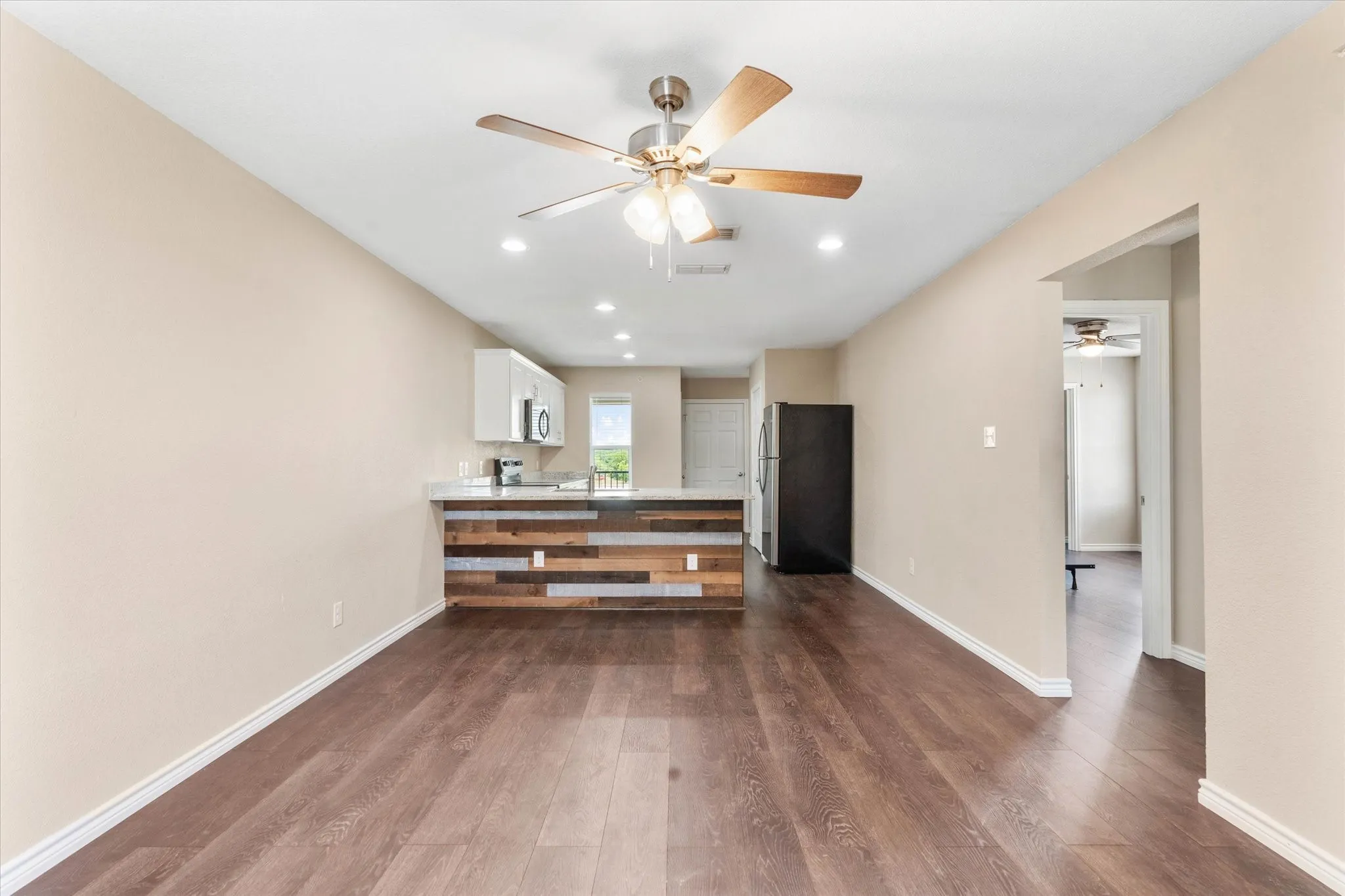 Kitchen with white cabinetry, ceiling fan, hardwood / wood-style floors, and stainless steel appliances