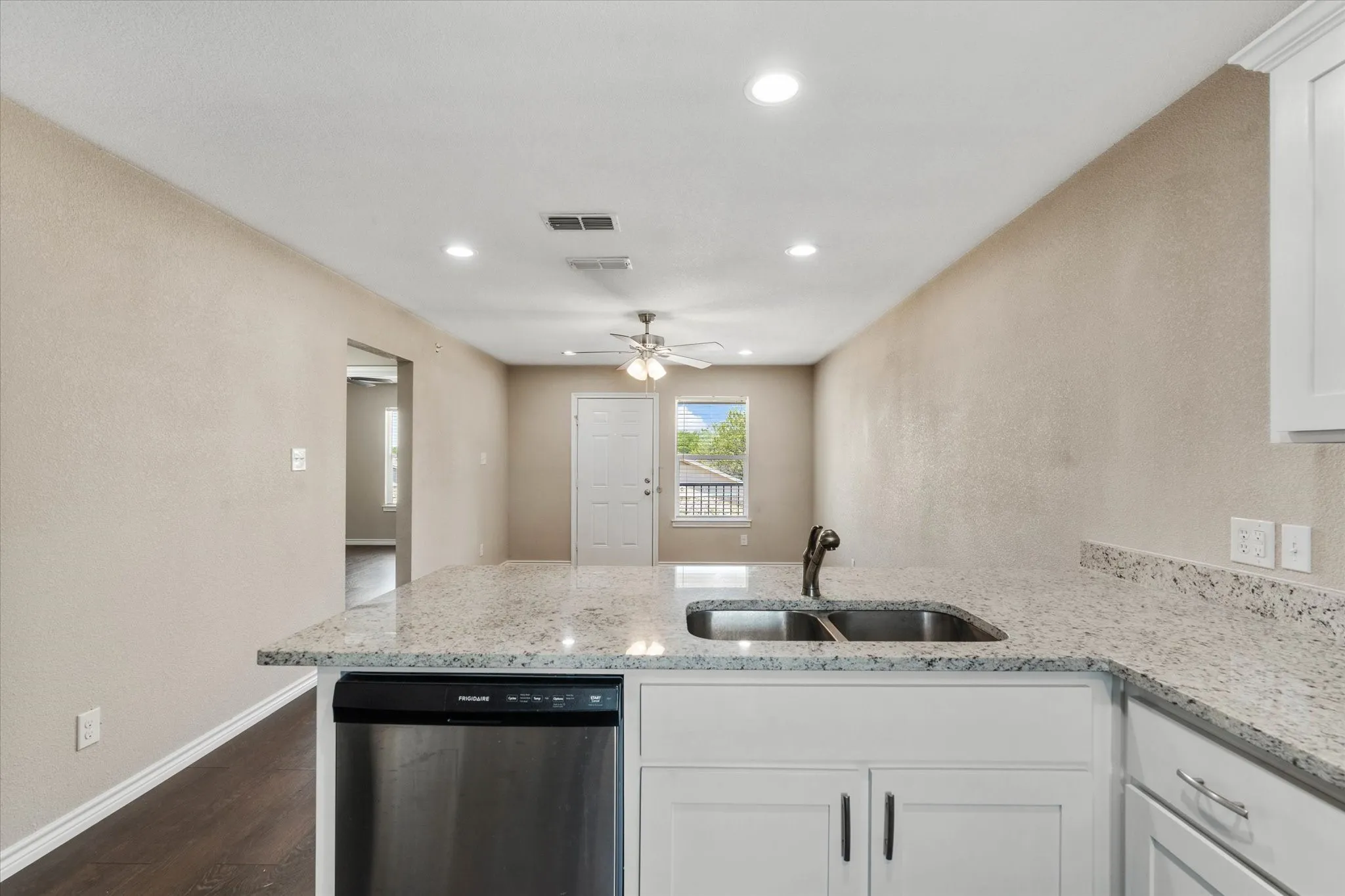 Kitchen featuring white cabinets, sink, ceiling fan, stainless steel dishwasher, and dark hardwood / wood-style flooring