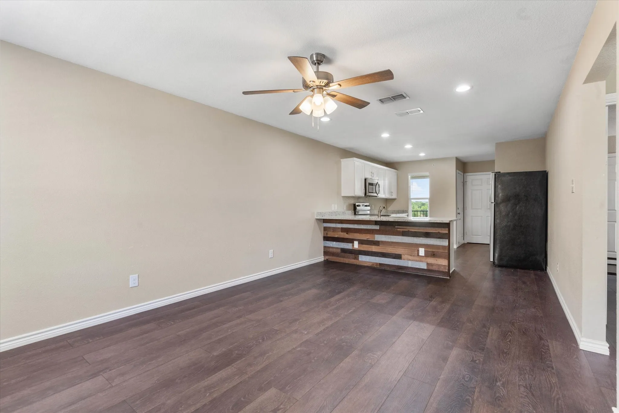 Unfurnished living room with dark hardwood / wood-style flooring and ceiling fan