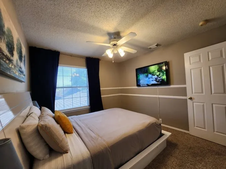 Carpeted flooring, ceiling fan with integrated lighting, window with blinds and drapes, chair rail molding, and a paneled door