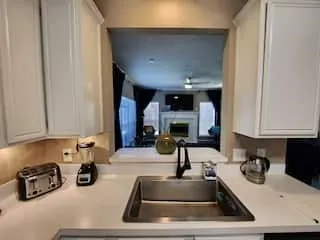 White shaker cabinetry, light countertops, undermount stainless steel sink, and a black gooseneck faucet