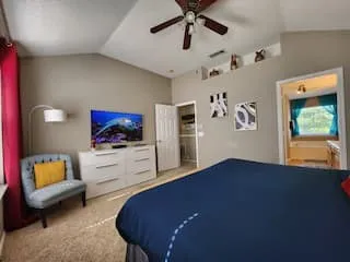Vaulted ceiling with a ceiling fan, wall alcove, and neutral wall tones